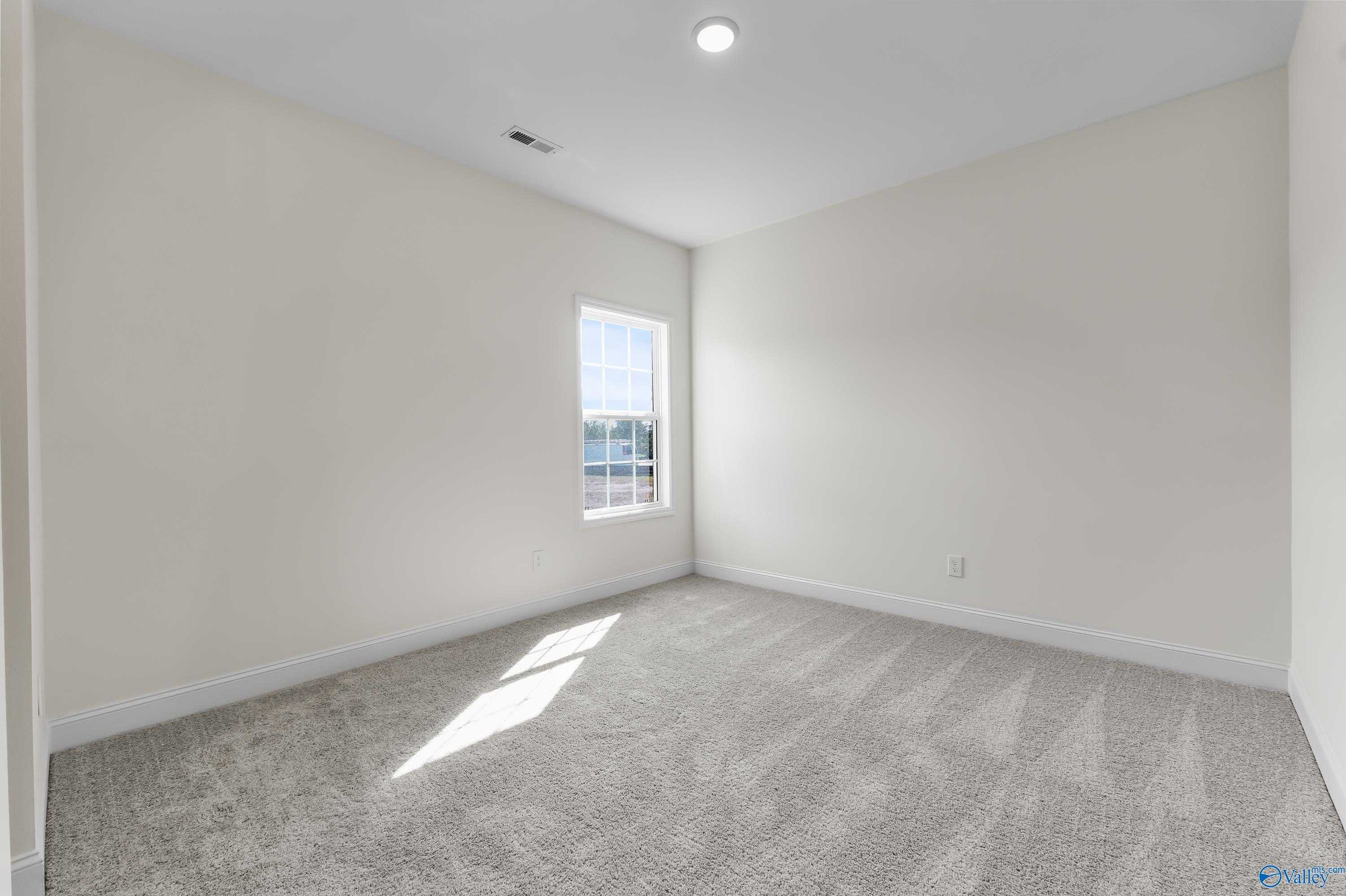 Bright secondary bedroom with neutral walls, plush carpet, large window, and natural light in Davidson Homes The Finleigh, Harvest, AL