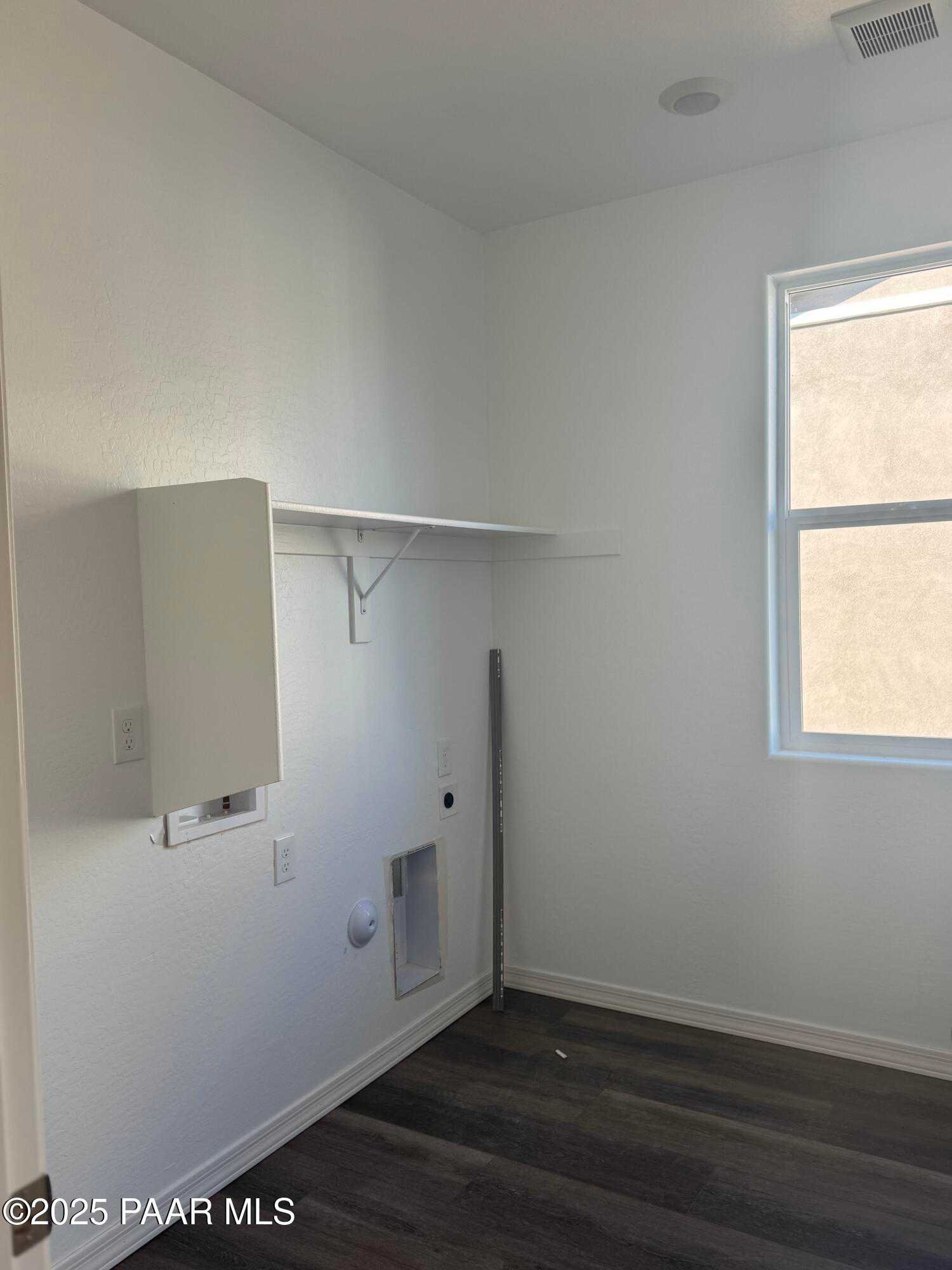 Bright laundry room with white cabinet, shelves, washer-dryer hookups, and window in Davidson Homes The Summit A, Prescott AZ