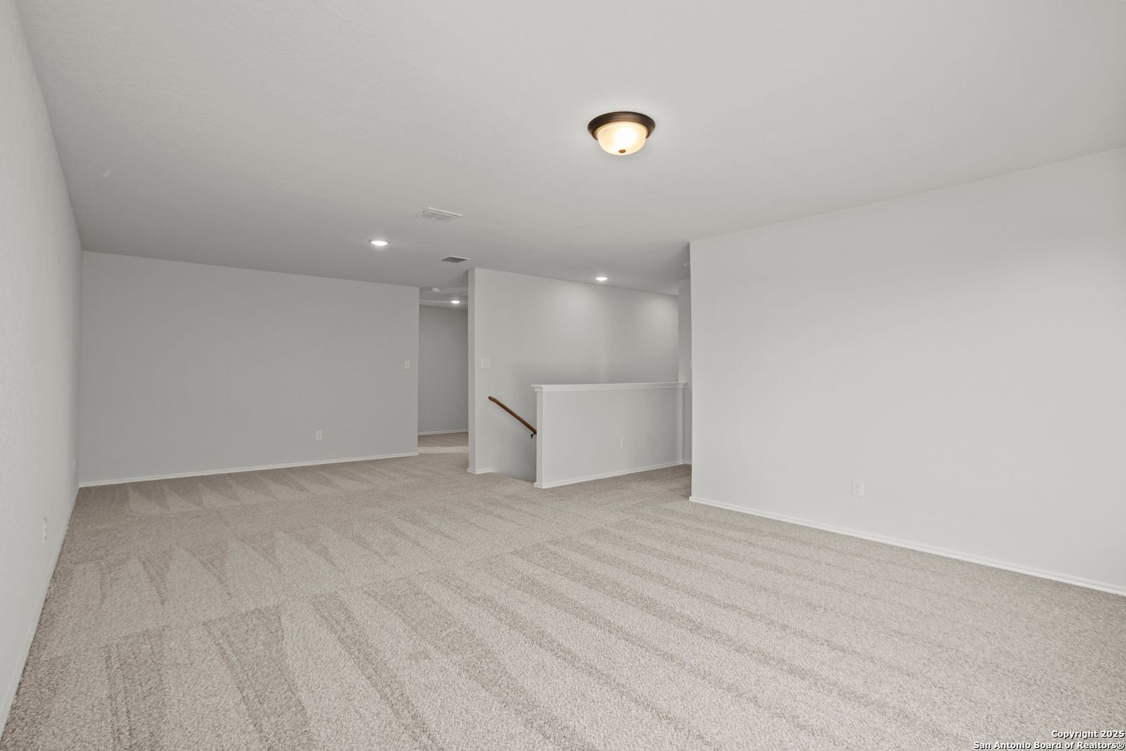 Spacious carpeted upstairs loft with staircase railing in Davidson Homes The Douglas C, Hannah Heights, Seguin, Texas