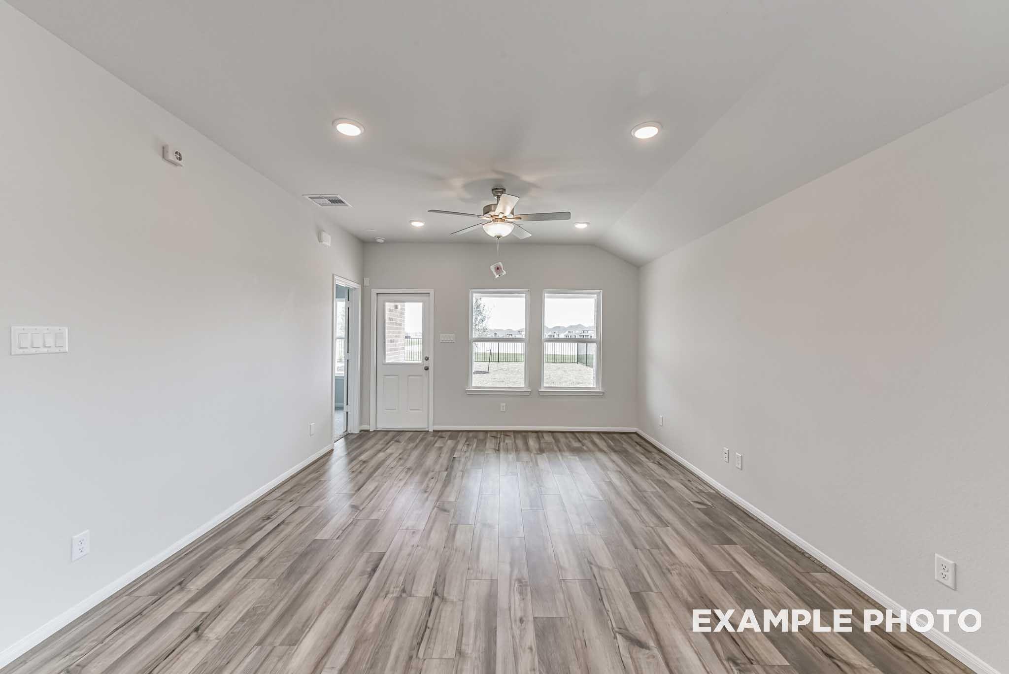 Bright living room with luxury vinyl plank flooring, ceiling fan, and recessed lighting in Davidson Homes The Costa A, Dayton, Texas