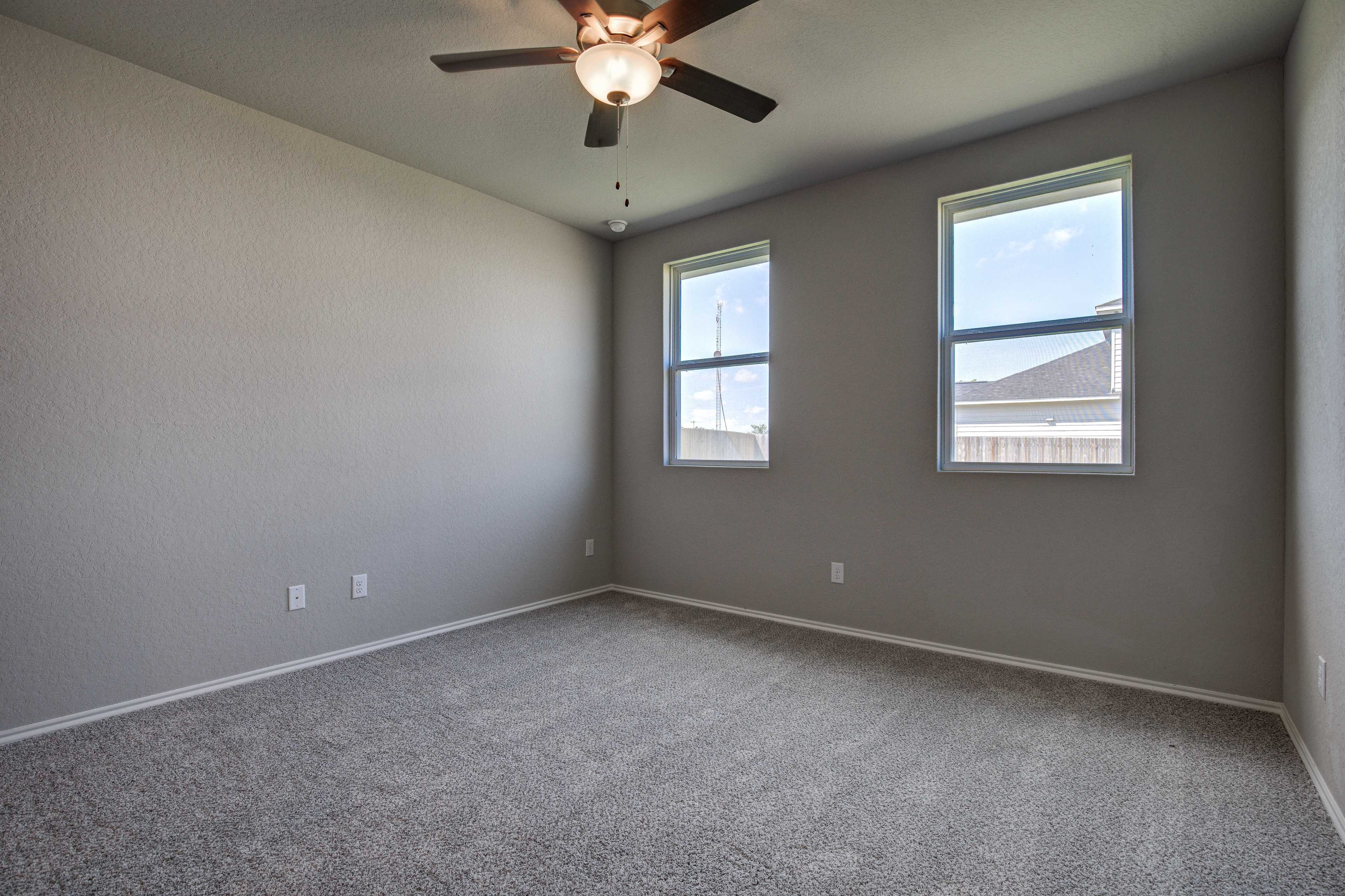 Spacious master bedroom in The Asheville with light gray walls, neutral carpet, ceiling fan, and large dual windows