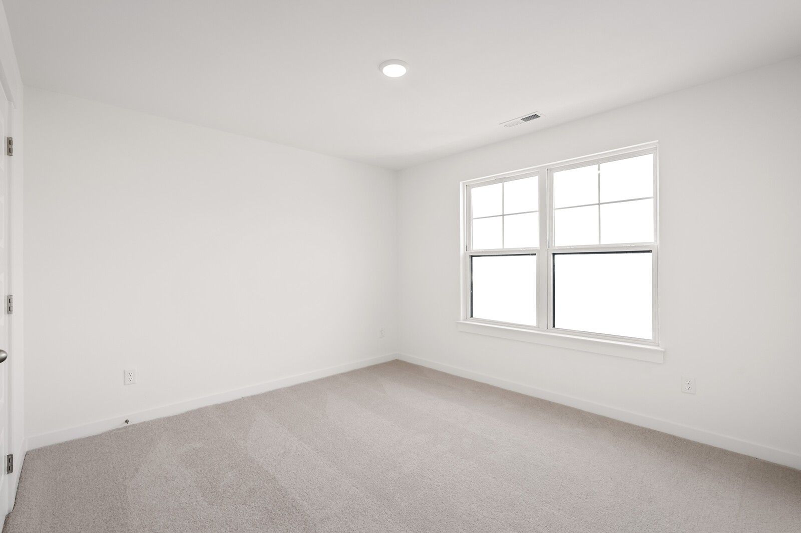 Bright empty bedroom with large double-hung window and neutral carpet in Davidson Homes The Ash C, Mt. Juliet, TN