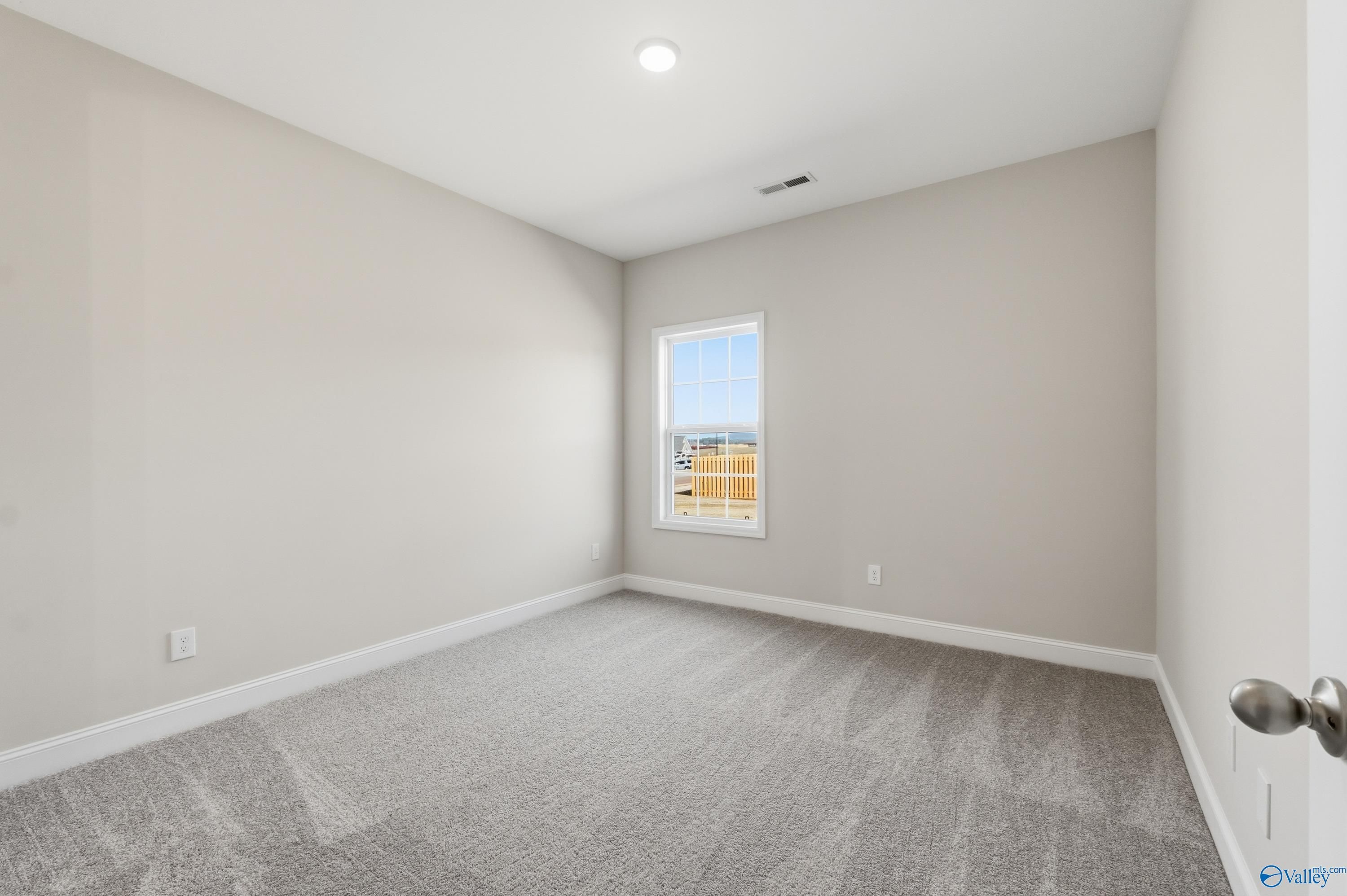 Bright secondary bedroom with beige walls, gray carpet, window view in Davidson Homes The Finleigh, Creekside, Harvest, AL