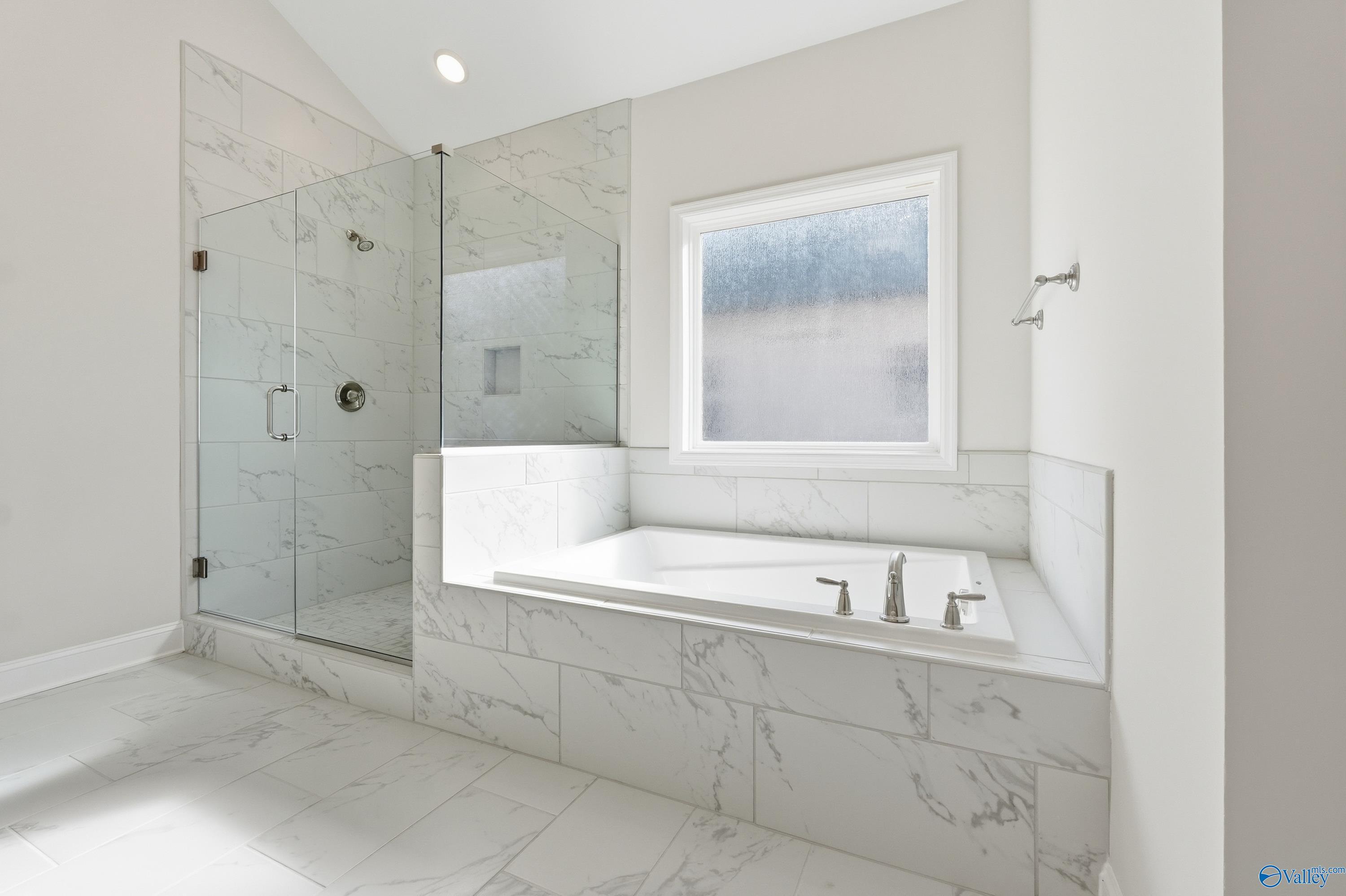 Luxurious master bathroom with frameless glass shower, freestanding soaking tub, and window in Davidson Homes The Finleigh, Harvest, Alabama