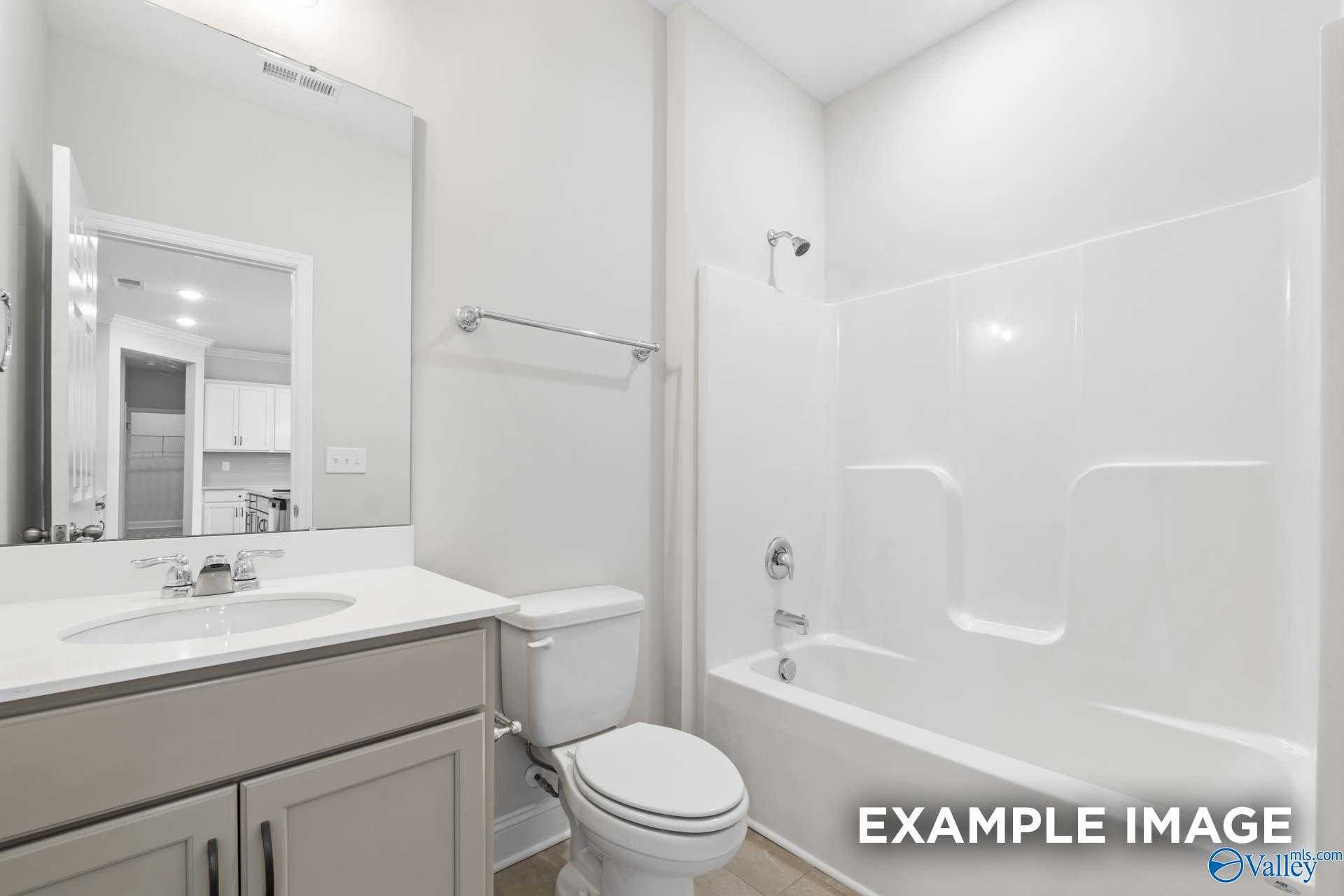 Bright secondary bathroom with white subway tile shower-tub combo, gray vanity, and modern fixtures in The Lanier home, Toney, Alabama