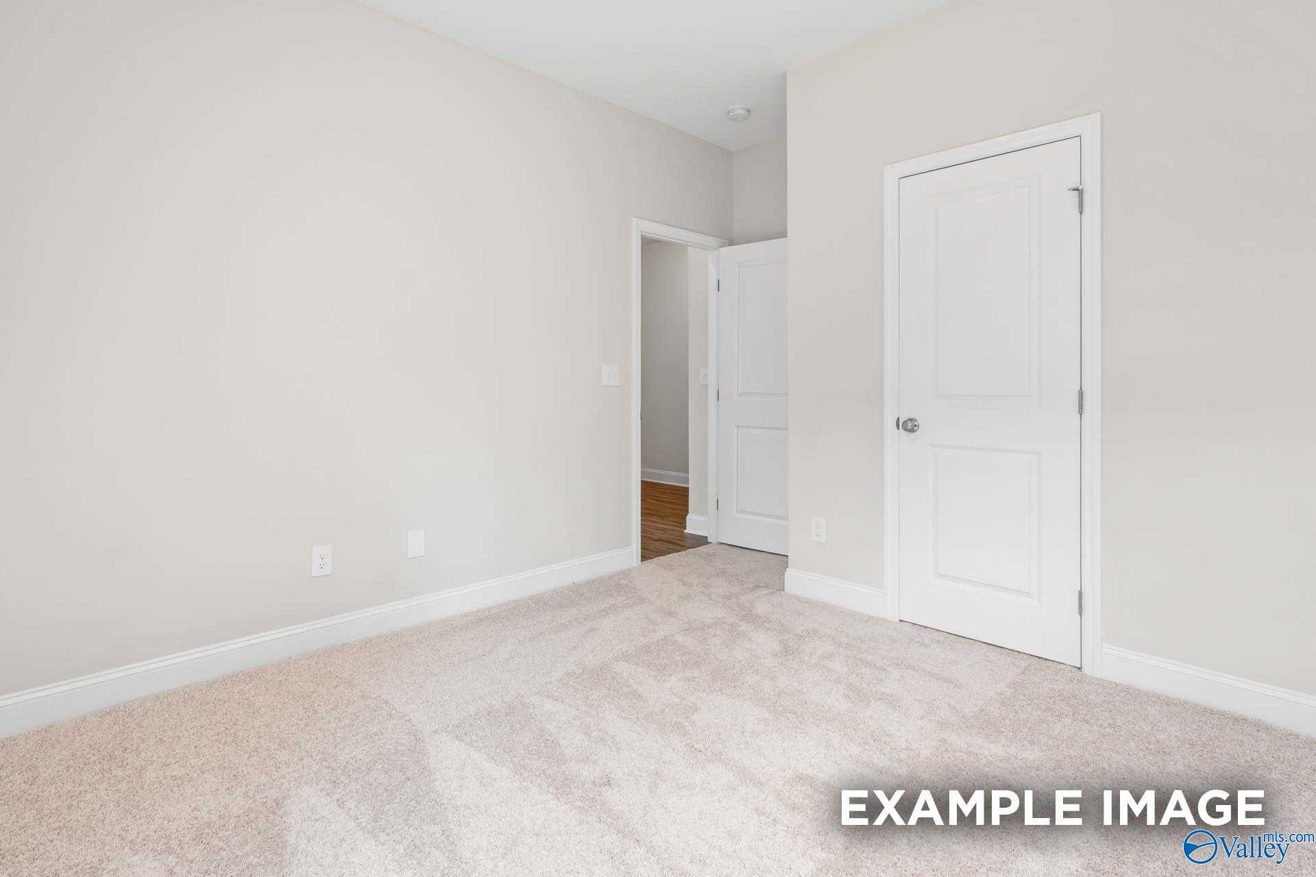 Bright secondary bedroom with neutral beige walls, plush carpet, and double doors in Davidson Homes The Franklin, Meridianville, Alabama
