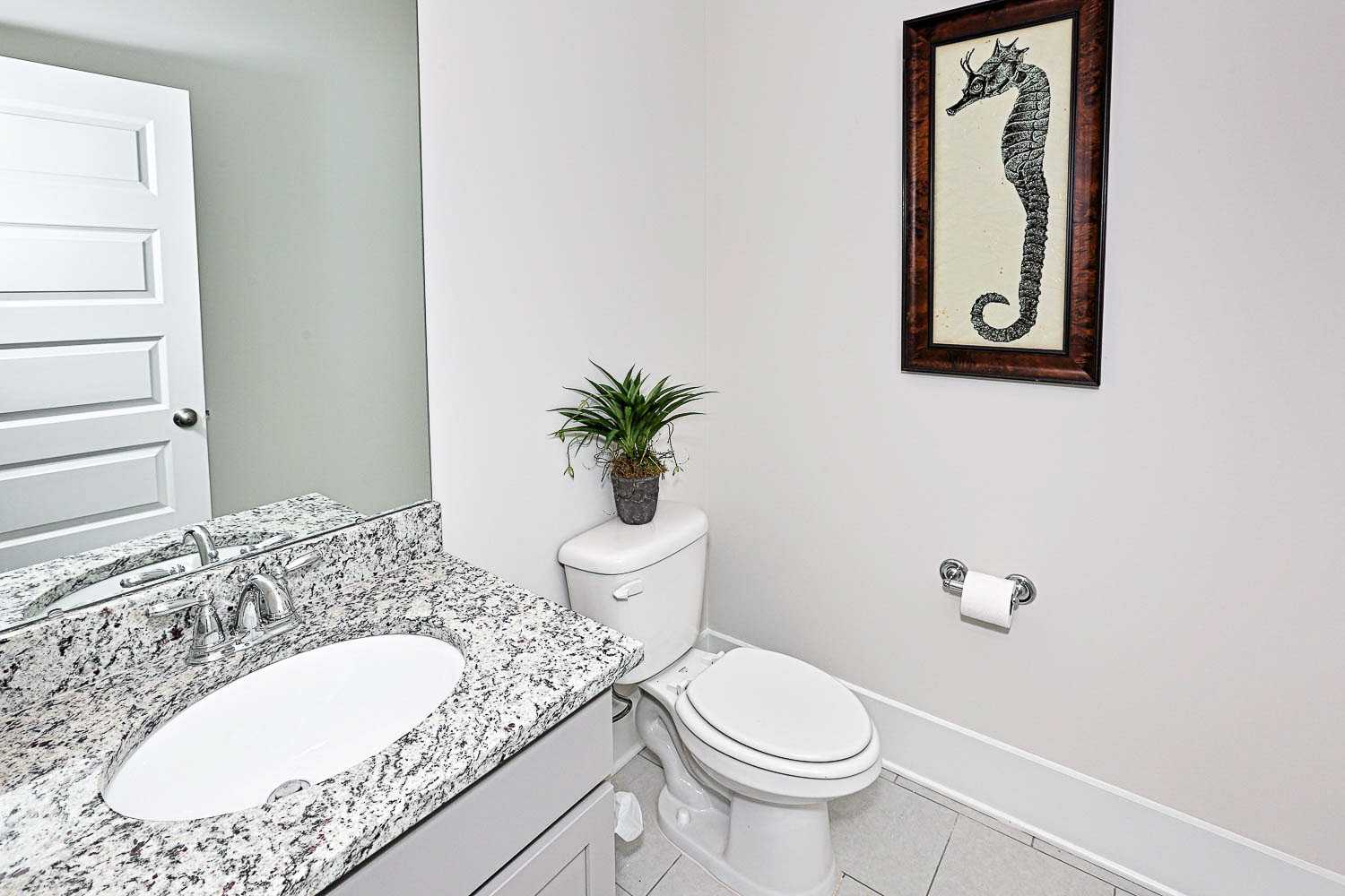 Spacious powder room in The Finleigh by Davidson Homes: granite vanity, white toilet, seahorse wall art, potted plant, Meridianville AL