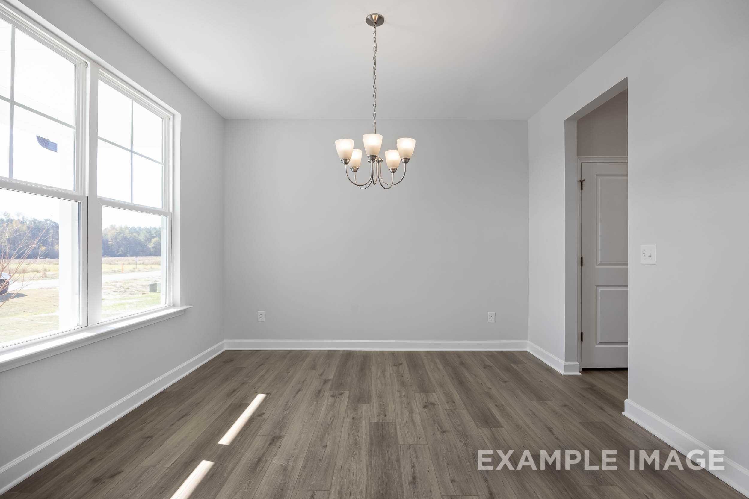 Spacious dining room in The Ash by Davidson Homes with hardwood floors, chandelier, and large sunny windows