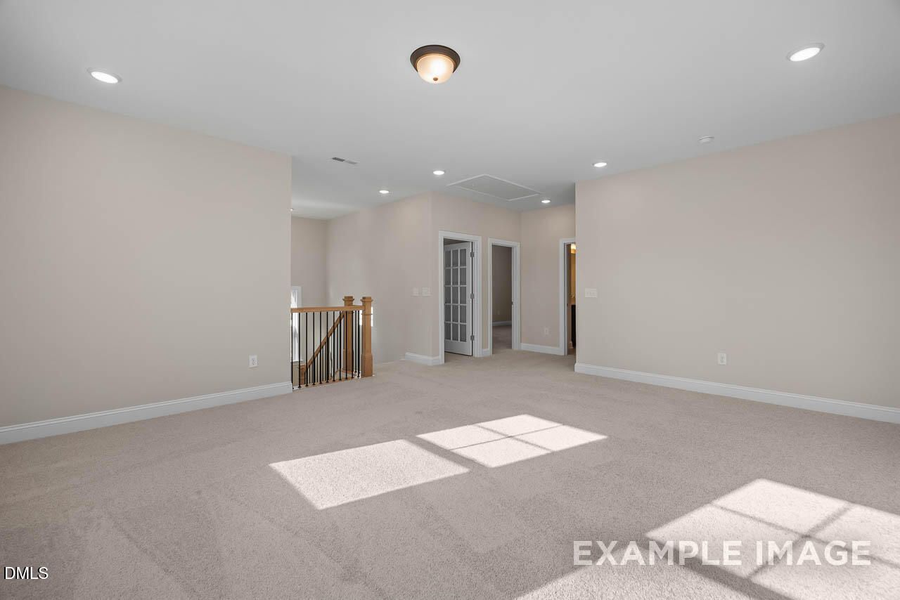 Spacious upstairs hallway with beige carpet, recessed lighting, oak staircase, and French doors in Davidson Homes Crawford D, Angier, NC