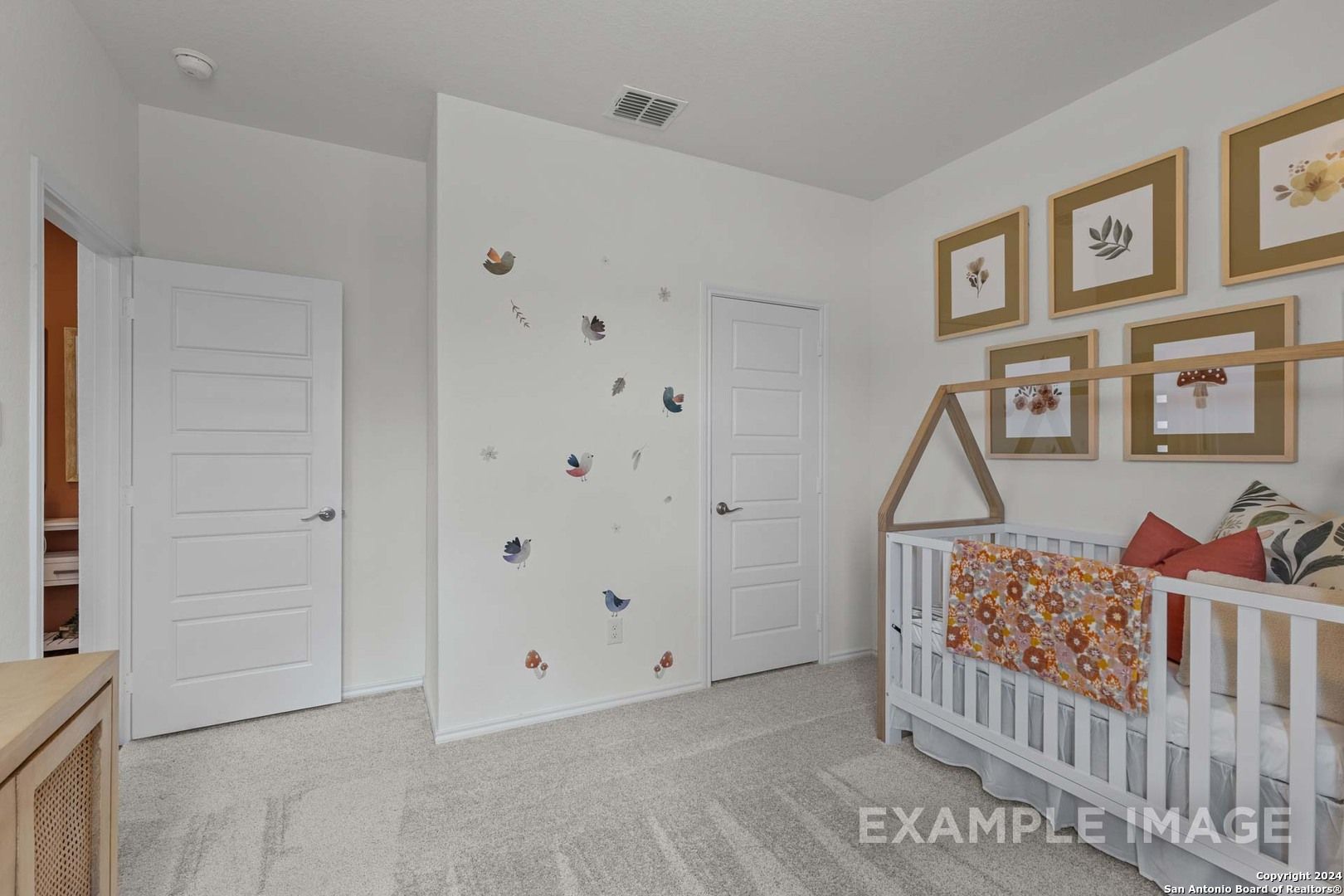 Charming nursery featuring white butterfly decals, wooden crib with floral bedding, and gold-framed botanical art in Davidson Homes The Daphne K, San Antonio