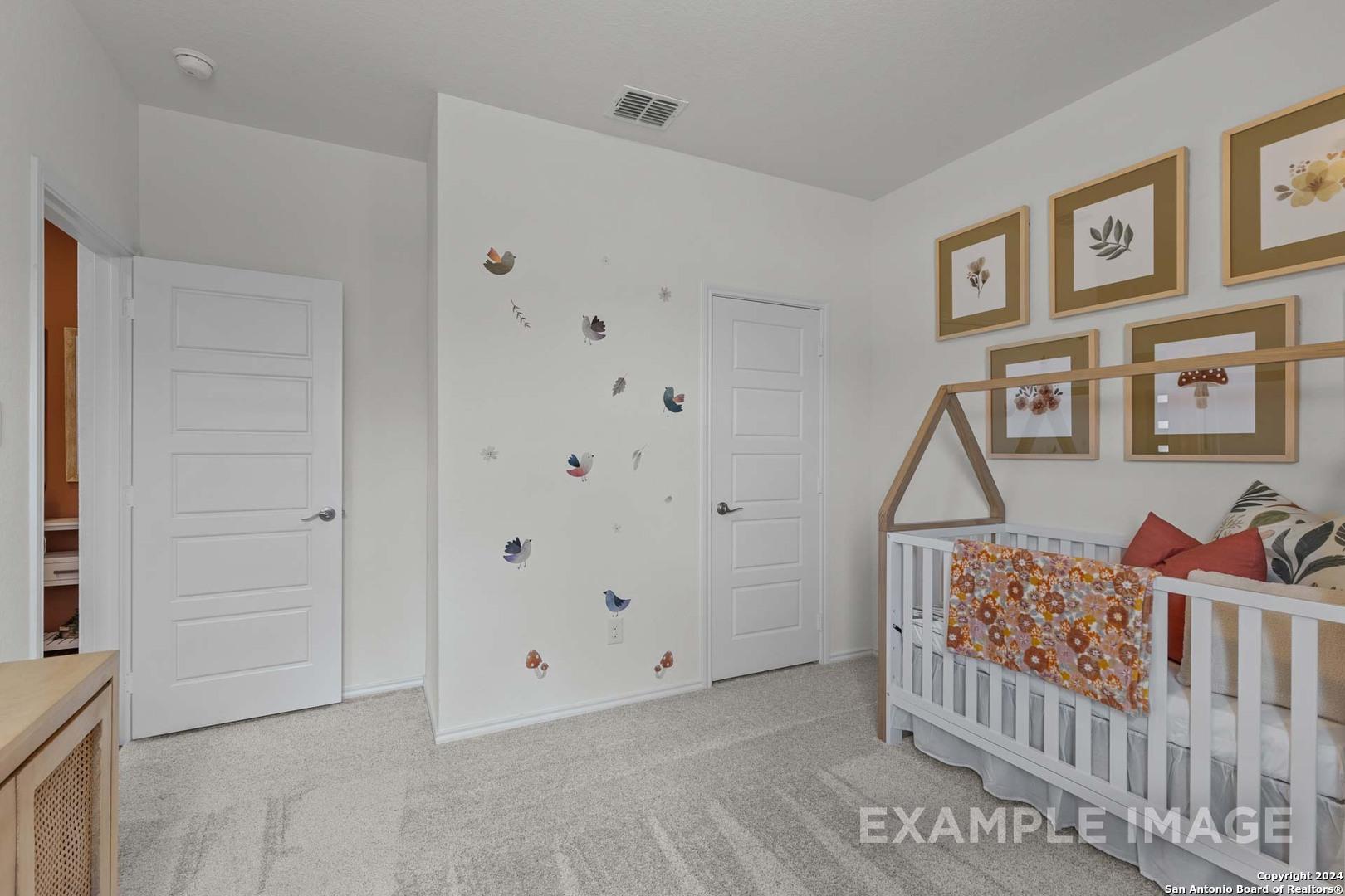 Charming nursery featuring white butterfly decals, wooden crib with floral bedding, and gold-framed botanical art in Davidson Homes The Daphne K, San Antonio