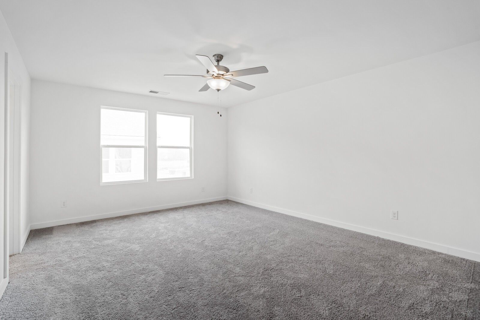 Bright bedroom with gray carpet, white walls, ceiling fan, and double windows in Davidson Homes The Logan B, Calista Farms, White House, TN