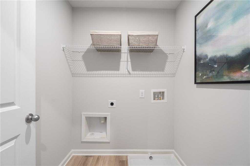Functional laundry room with wire shelving, woven baskets, and washer-dryer hookups in Davidson Homes Wilmington B, Emerson, GA