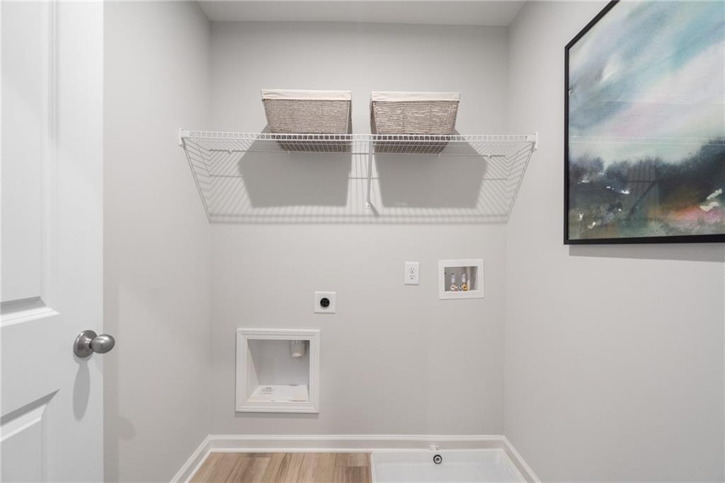 Organized laundry room with wire shelving, wicker baskets, washer-dryer hookups in Davidson Homes The Wilmington B, Emerson, Georgia