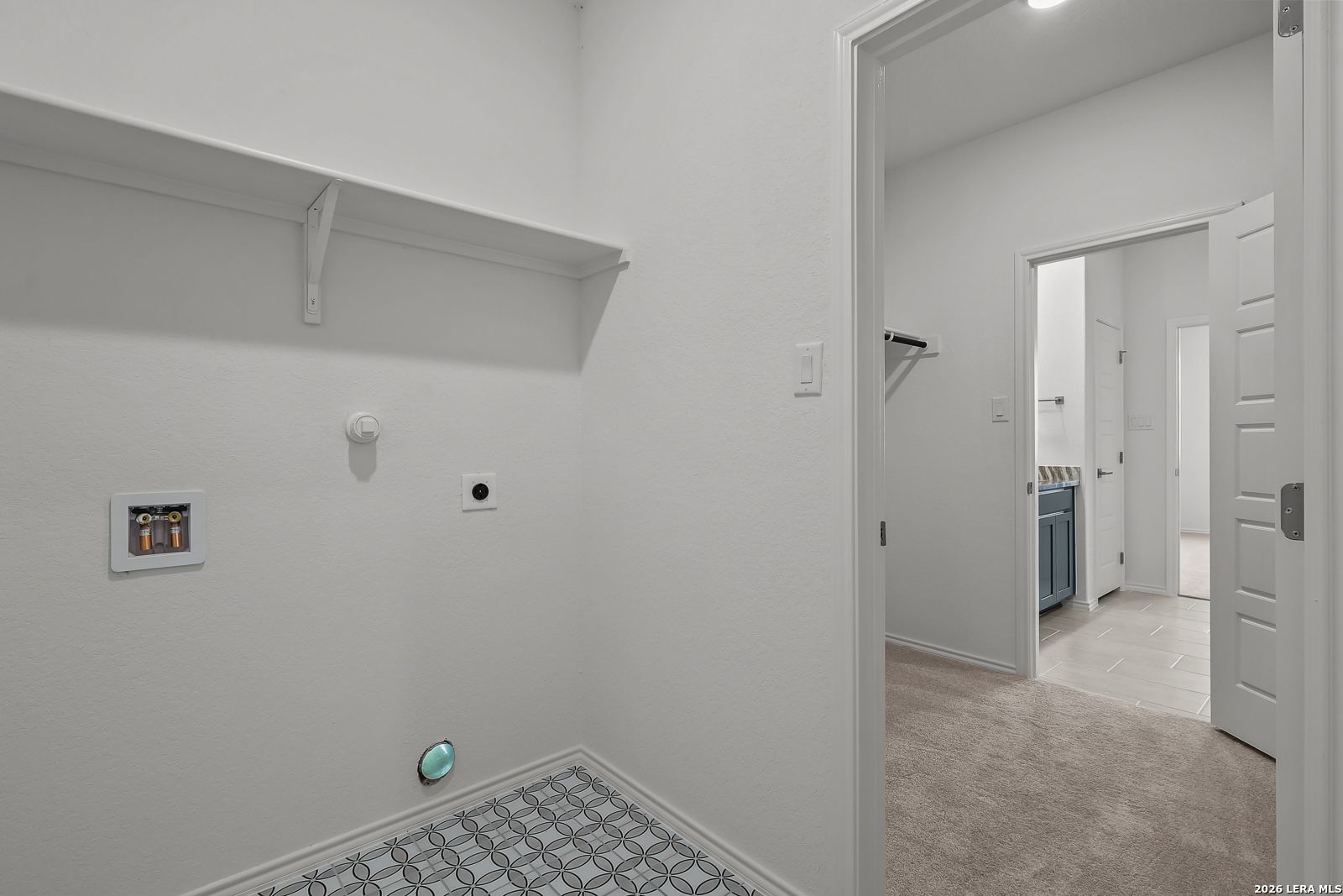 Laundry room with patterned tile flooring and shelf in The Brazos B floor plan by Davidson Homes in Agave, San Antonio.