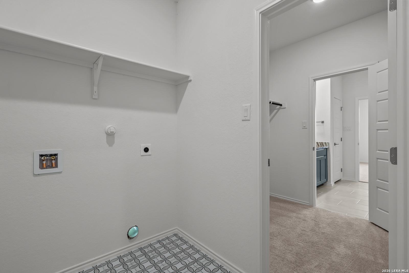 Laundry room with patterned tile flooring and shelf in The Brazos B floor plan by Davidson Homes in Agave, San Antonio.