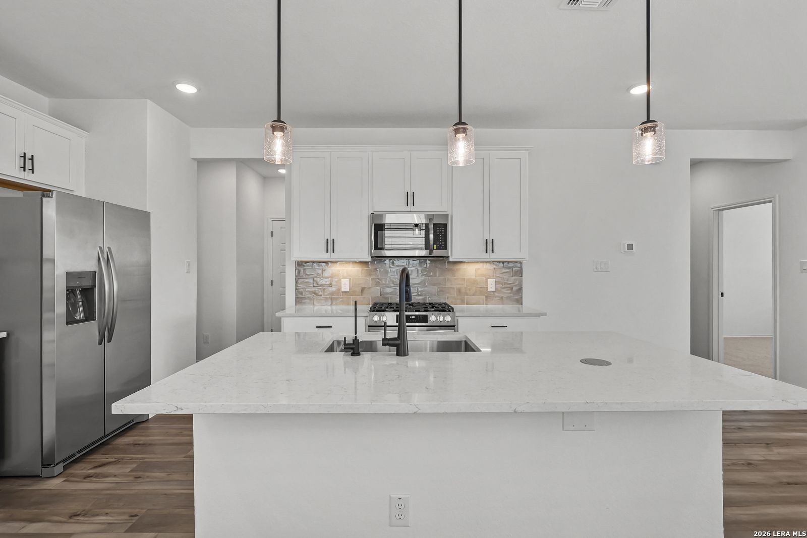 Modern kitchen with white cabinets, quartz island, and stainless steel appliances in Gillian C plan at Meadows at Oak Creek.