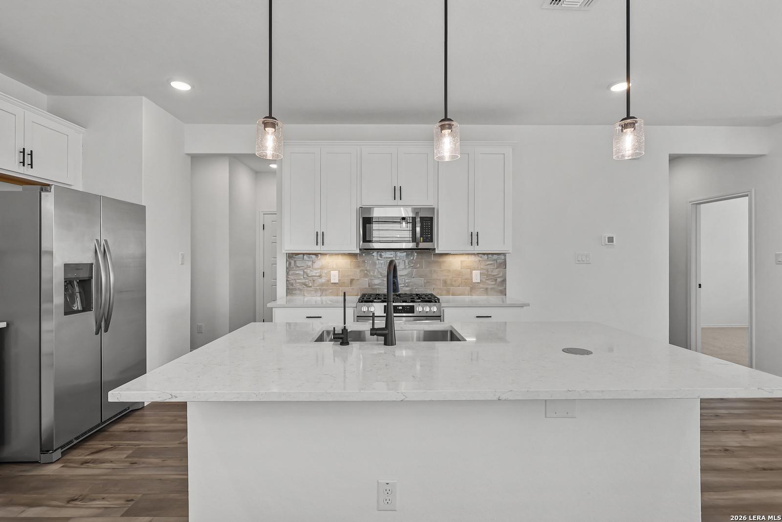 Modern kitchen with white cabinets, quartz island, and stainless steel appliances in Gillian C plan at Meadows at Oak Creek.