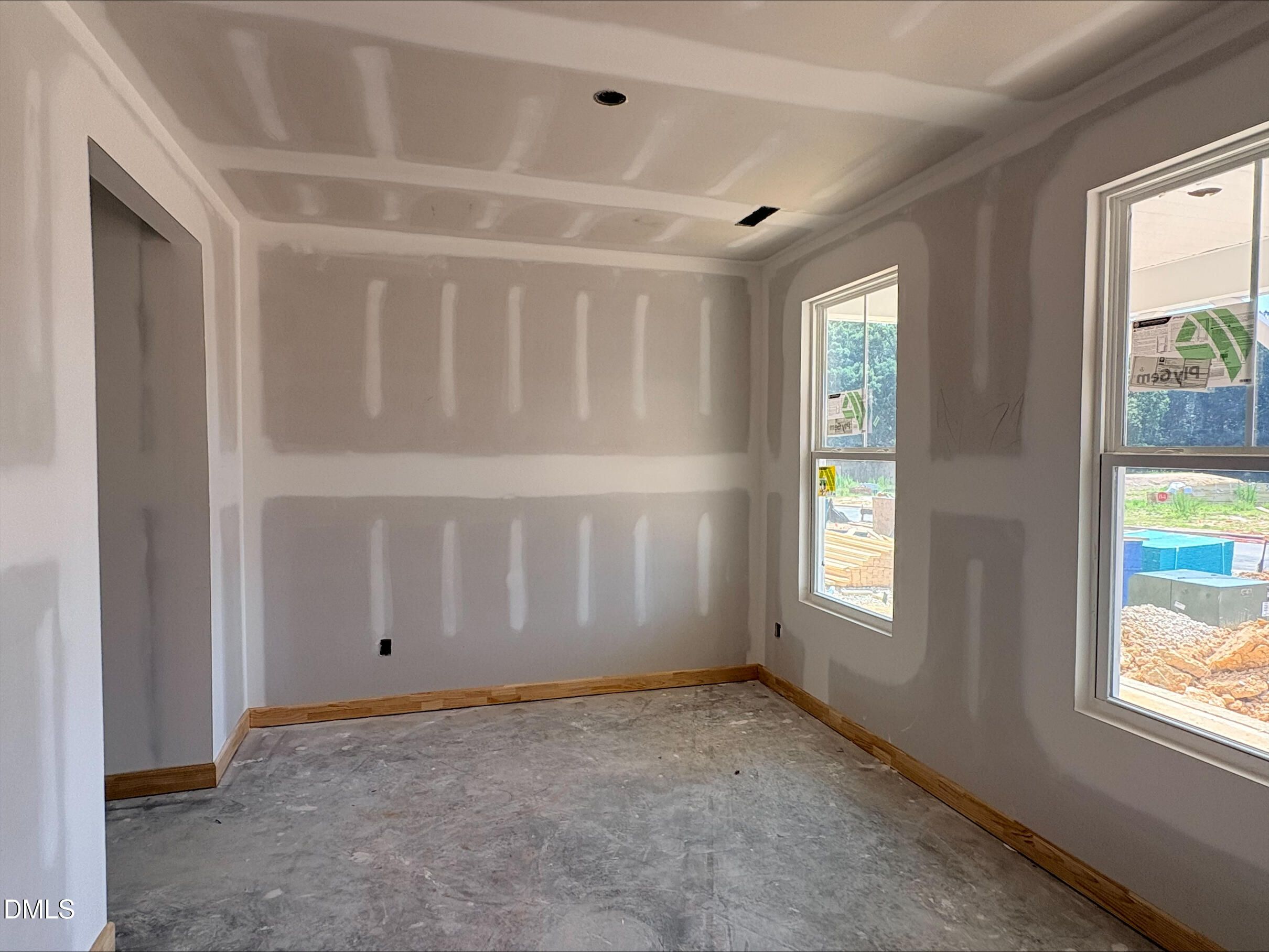 Unfinished bedroom with drywall and windows in The Willow B floor plan at Woodland Crossing in Zebulon, North Carolina.