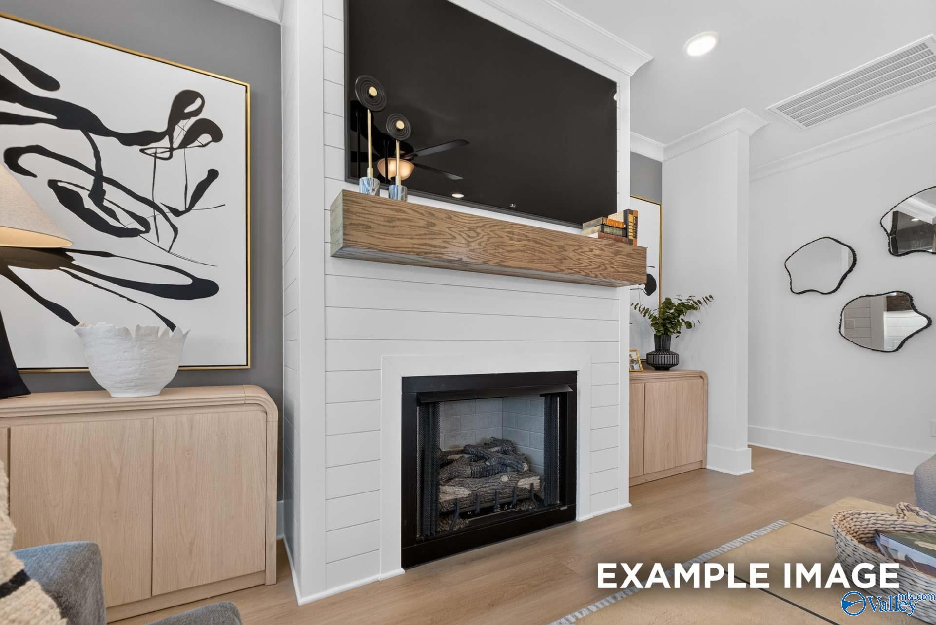 White shiplap fireplace with rustic wood mantel and mounted TV in Davidson Homes The Ashport K living room, Hazel Green, Alabama