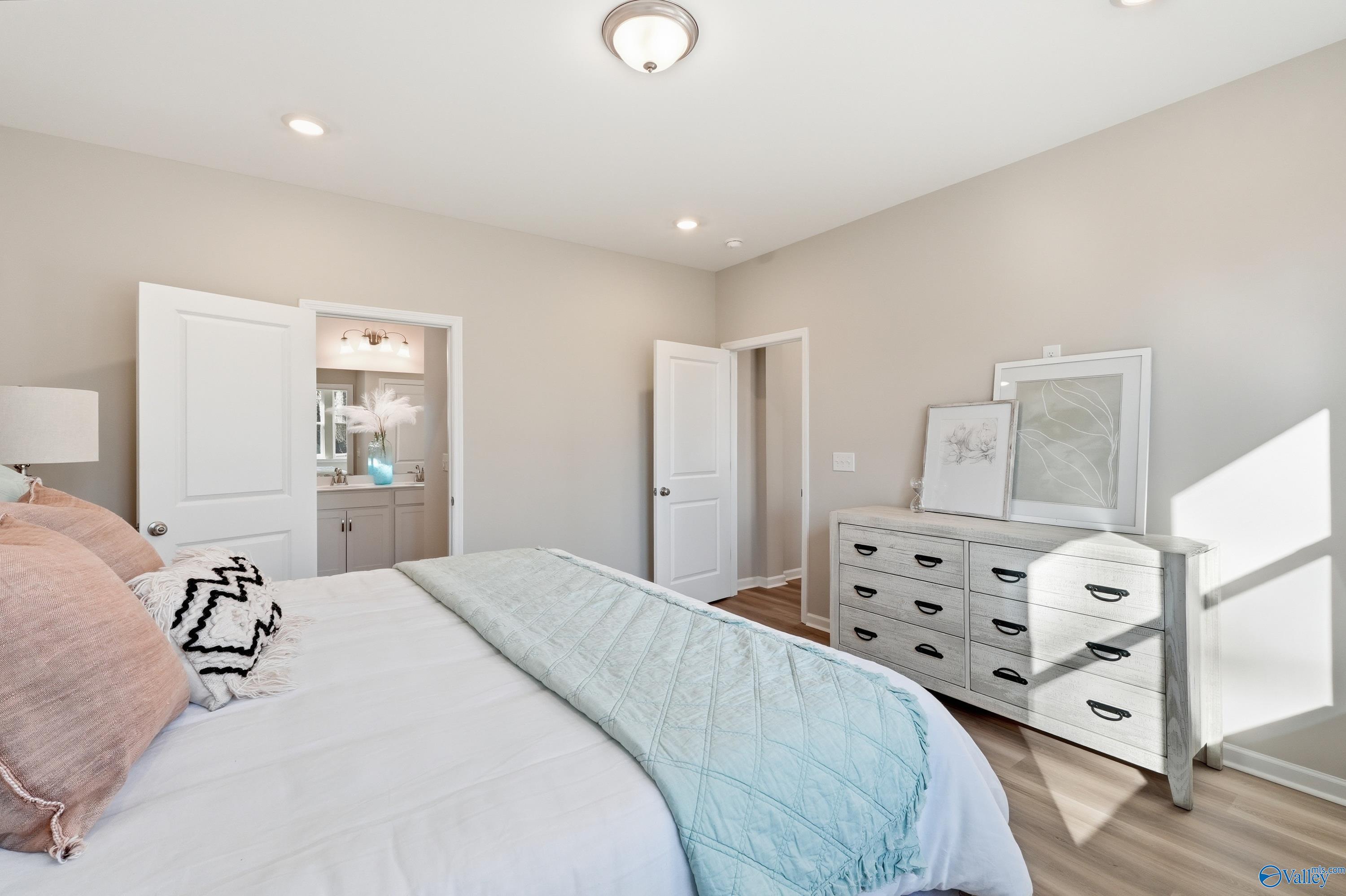 Cozy master bedroom with king bed, pink pillows, blue quilt, white dresser, and en-suite bath in Davidson Homes The Polaris, Fayetteville, TN