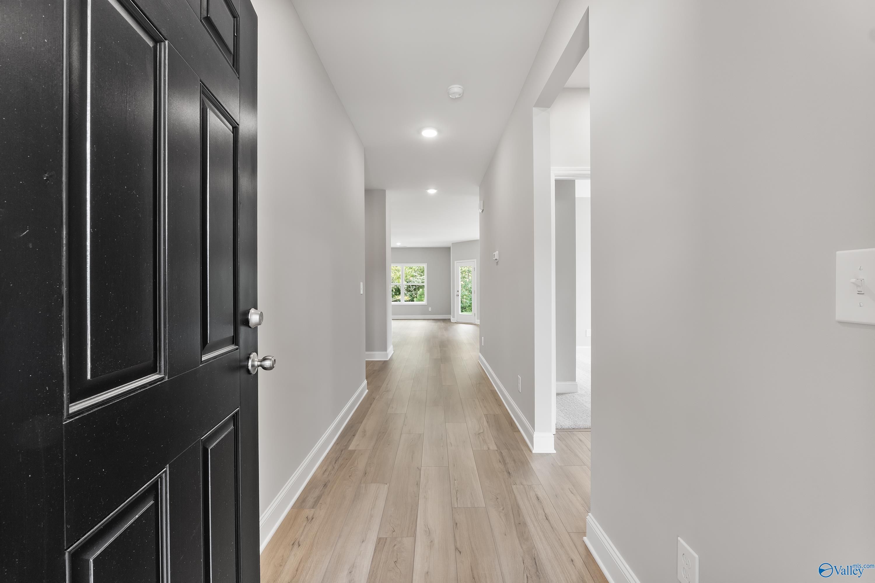 Open front door to welcoming hallway with light hardwood floors, gray walls, and recessed lighting in Davidson Homes The Franklin, Huntsville, Alabama