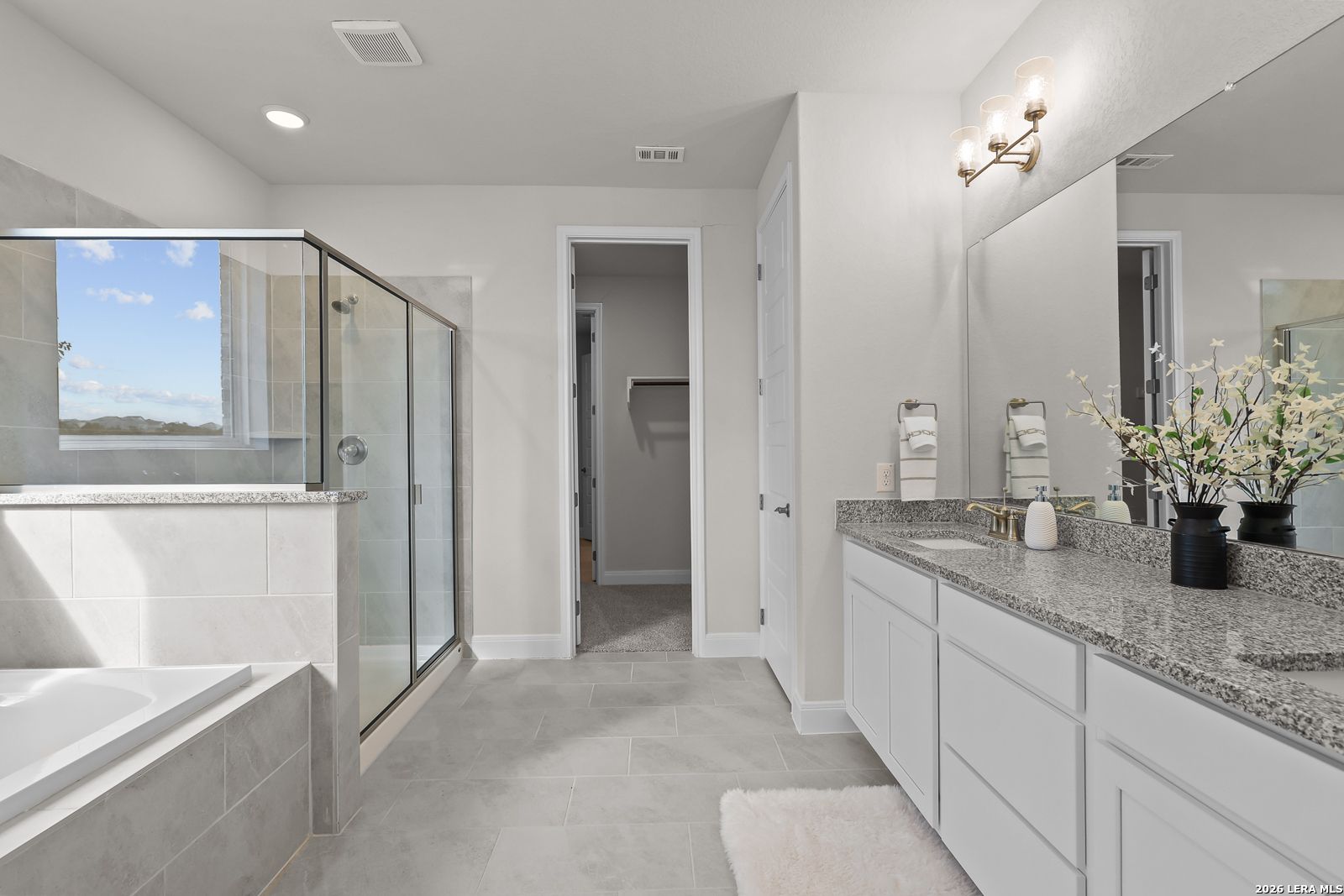 Modern primary bathroom with granite vanity, walk-in shower, and soaking tub in The Lanier H floor plan in Ladera, SA.