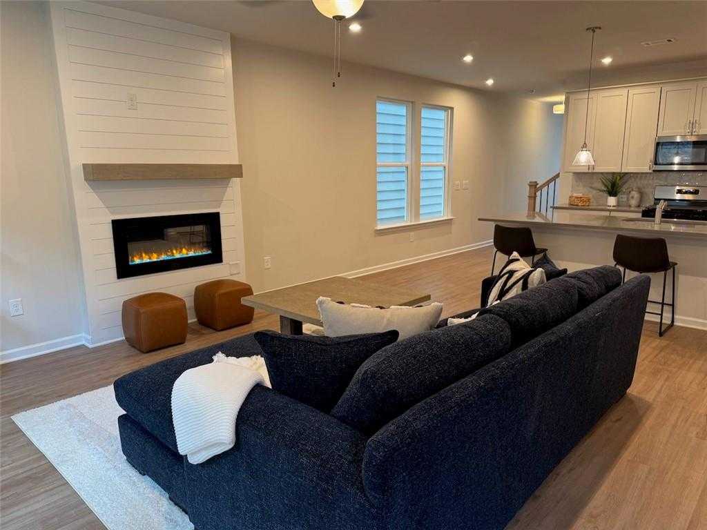 Cozy living room with linear gas fireplace, navy sectional sofa, and open kitchen in Davidson Homes The Cary A, Kennesaw, GA