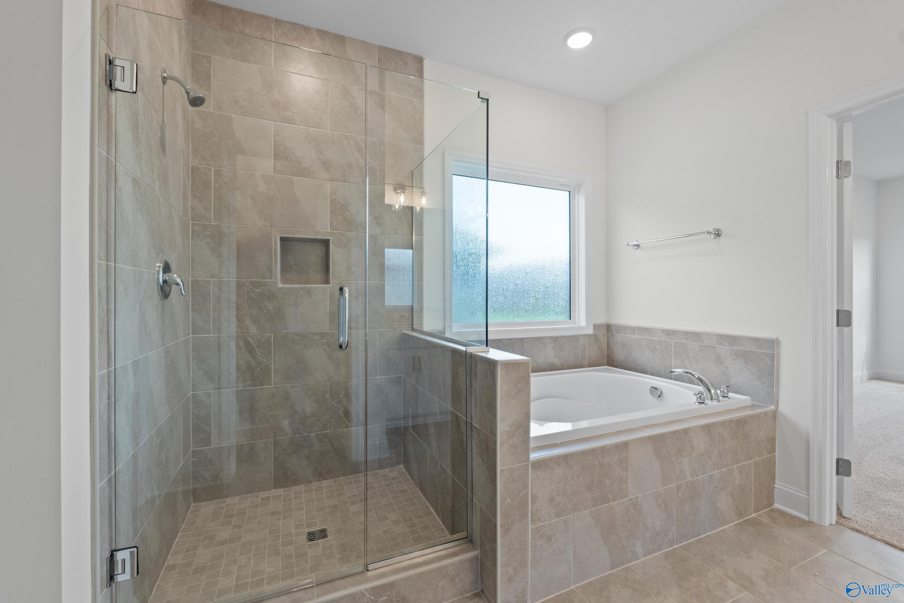 Modern master bathroom with tiled glass shower, soaking tub, and frosted window in Davidson Homes The Rockford B, Toney, Alabama