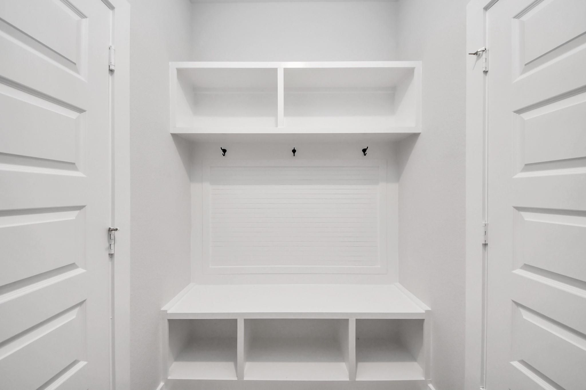 White mudroom bench with built-in storage cubbies and coat hooks in The Sabine E floor plan at Liberty Estates, Cleveland.