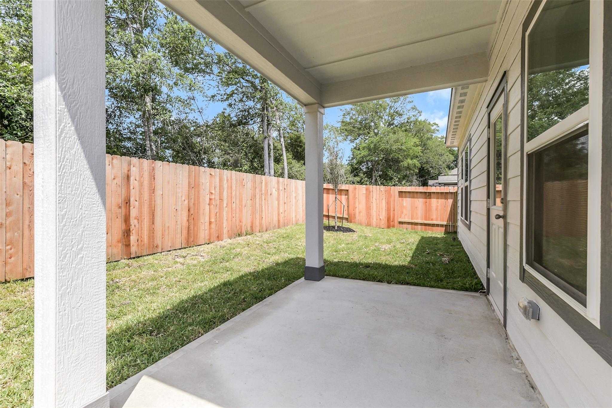 Covered back patio with wooden fence and green lawn in Davidson Homes Sabine E, Caney Creek Place, Conroe, Texas