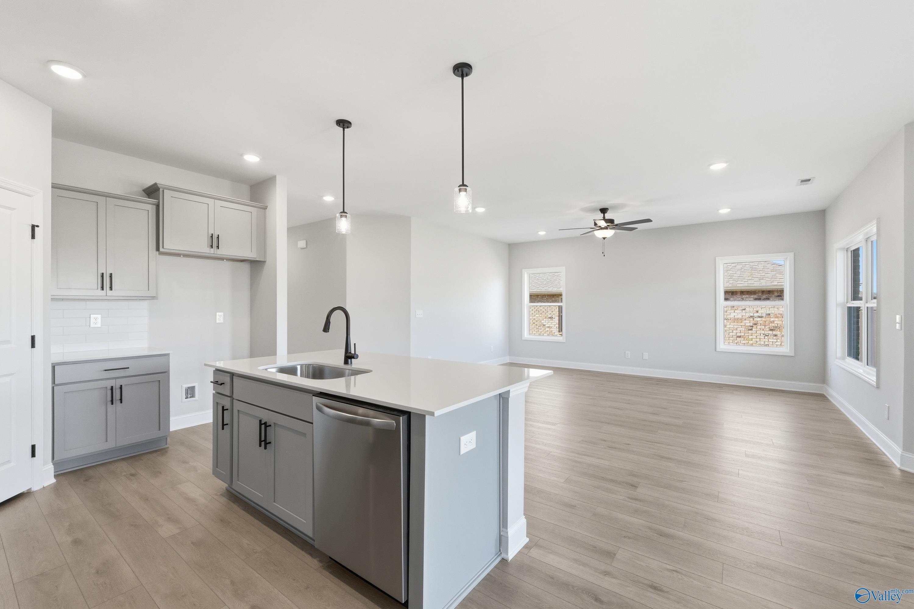 Modern open-concept kitchen with gray island, pendant lights, and ceiling fan in Davidson Homes The Franklin C, New Market, Alabama
