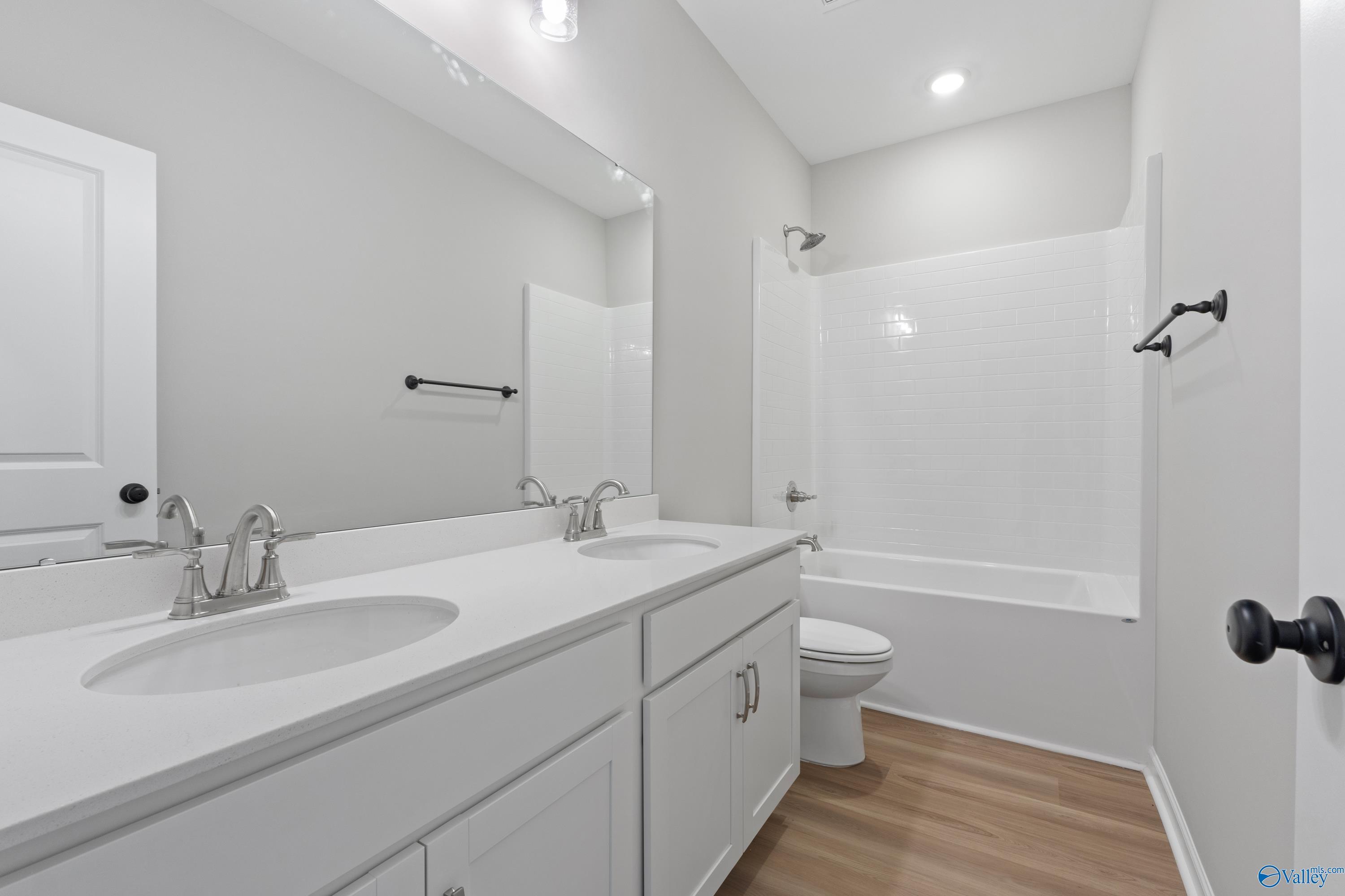 Modern guest bathroom featuring double vanity, bathtub shower combo, and white cabinetry in Davidson Homes The Phoenix, Fayetteville, TN