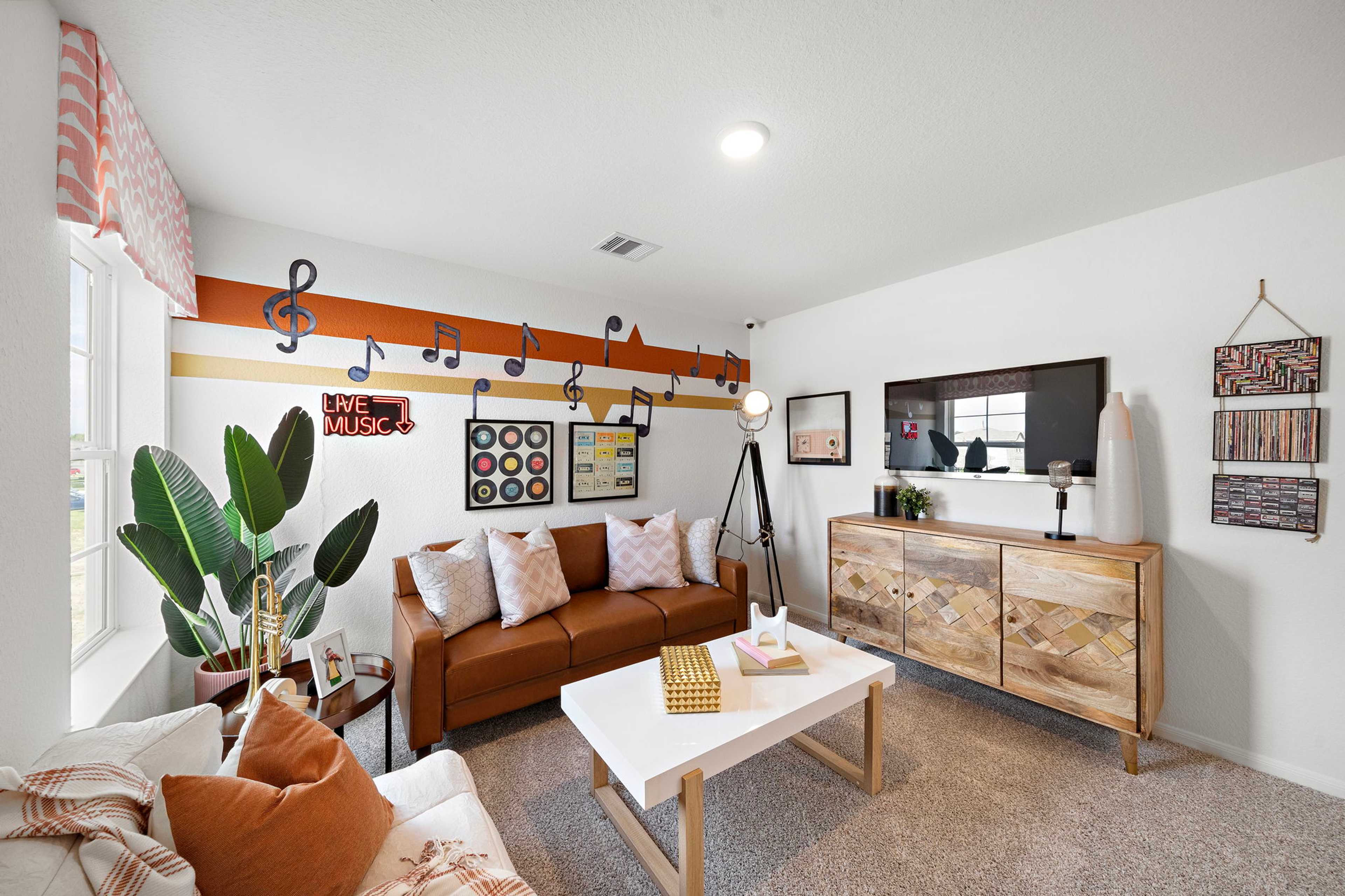 Music-themed media room at The Villages at WestPointe in Dayton TX with leather sofa, TV, rock posters, vinyl records, and potted plant