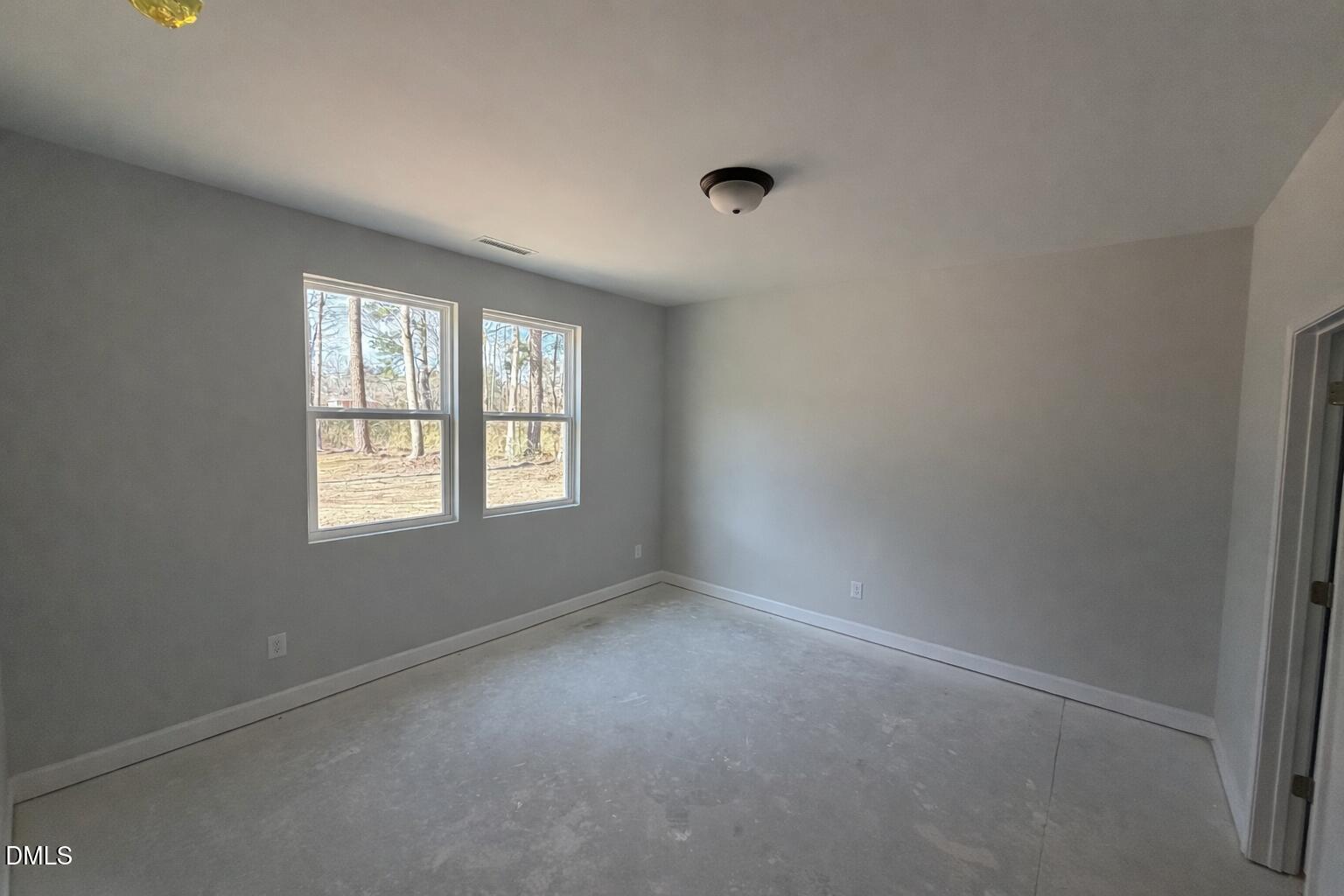 Spacious empty bedroom with large windows overlooking pine trees, light gray walls, carpeted floor in Davidson Homes Carter C, Lillington, NC