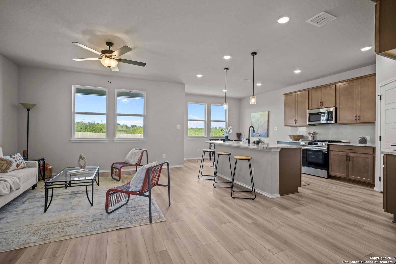 Bright open-concept living room with sofa, red chairs, and kitchen island in The Asheville H home, Converse, Texas