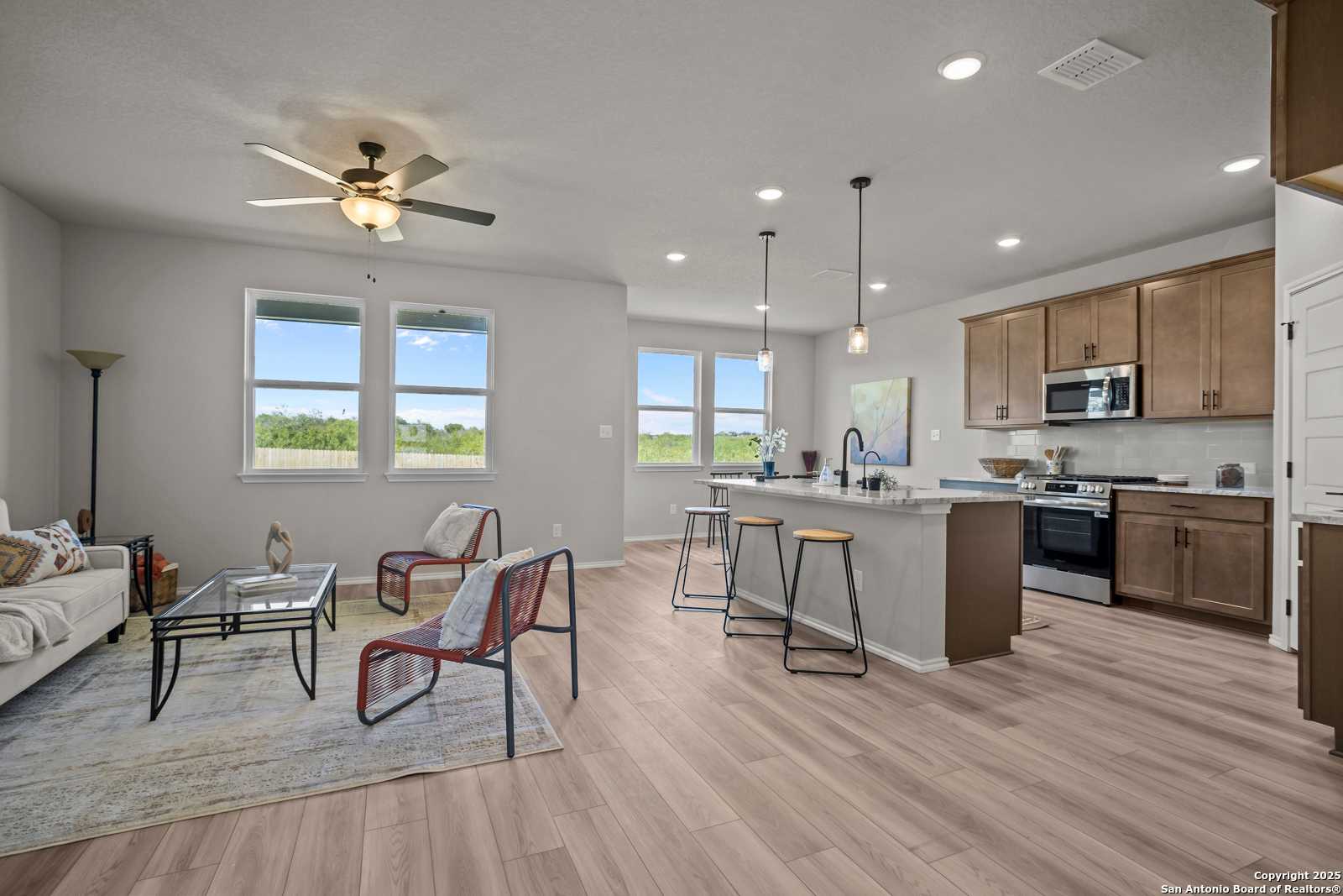 Bright open-concept living room with sofa, red chairs, and kitchen island in The Asheville H home, Converse, Texas