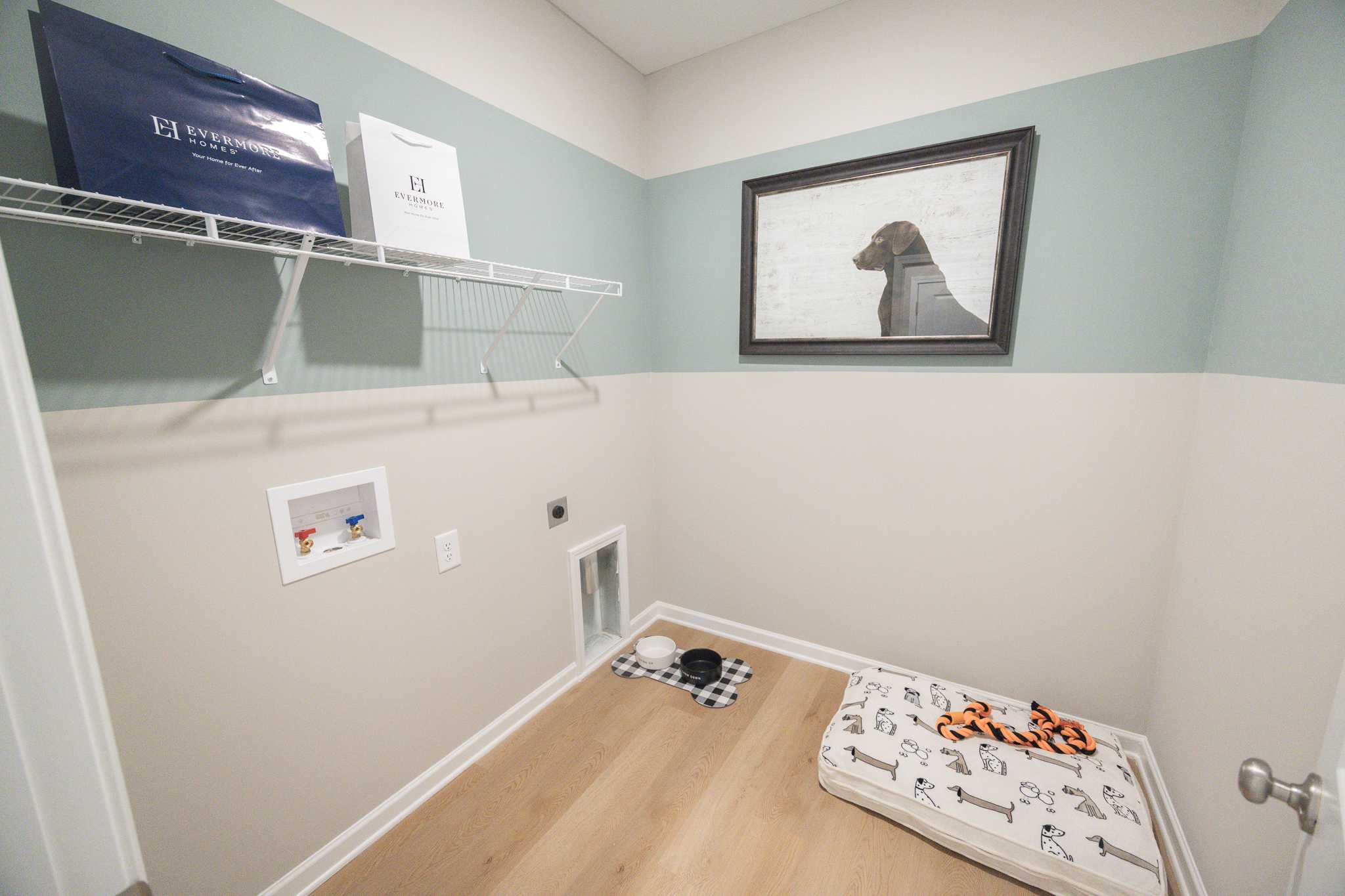 Cozy pet room with dog bed, bowls, pet door, and washer-dryer in Silver Oak, Cusseta Alabama by Evermore Homes