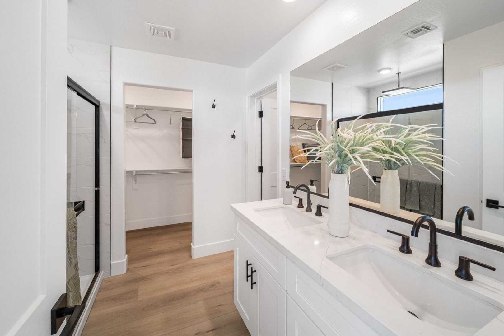 Spacious master bathroom at South Ranch Southern Collection in Prescott AZ with white double vanity, black-framed walk-in shower, and adjacent closet