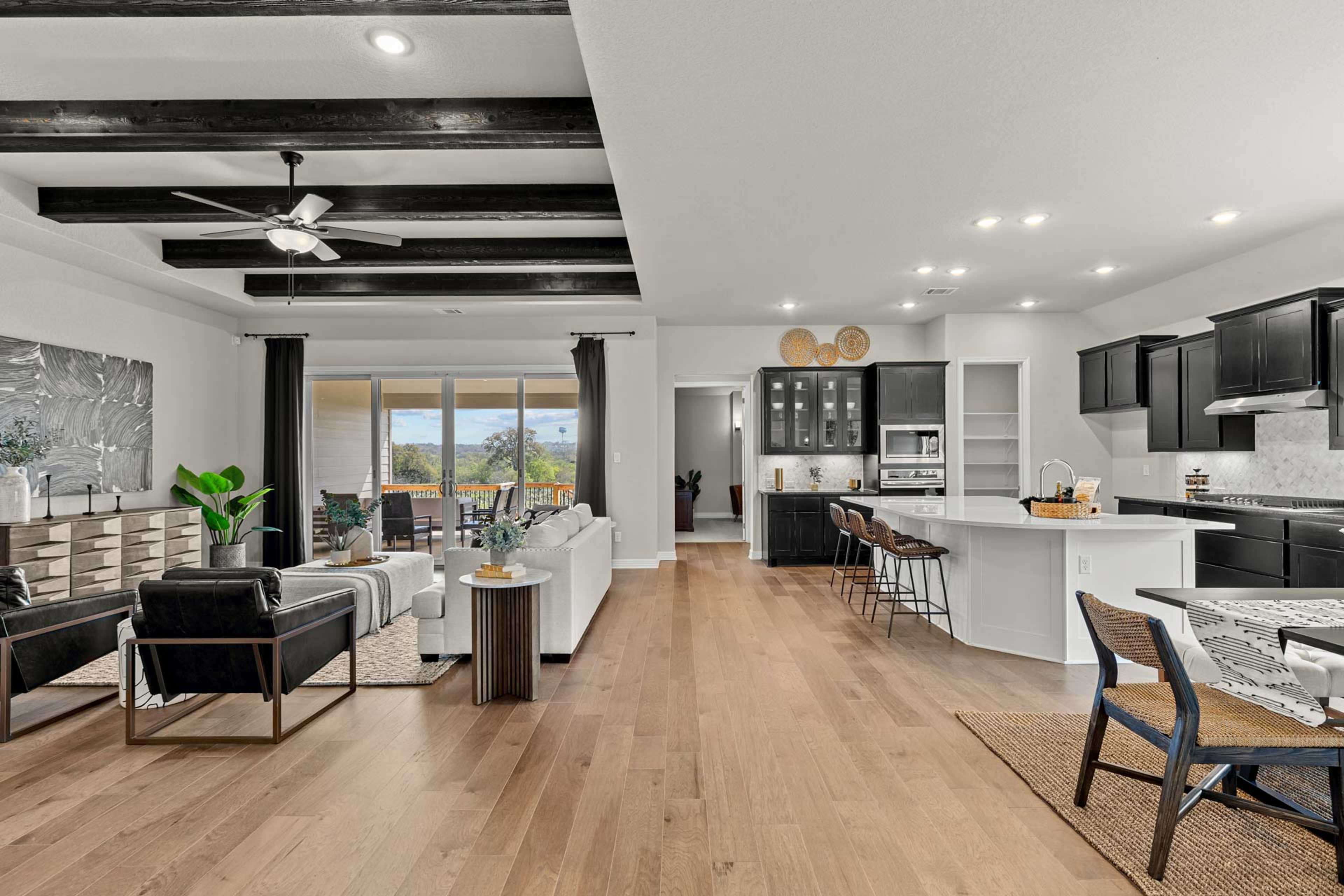 Open-concept living room and kitchen at Potranco Oaks in Castroville, Texas with hardwood floors, beamed ceiling, and modern island