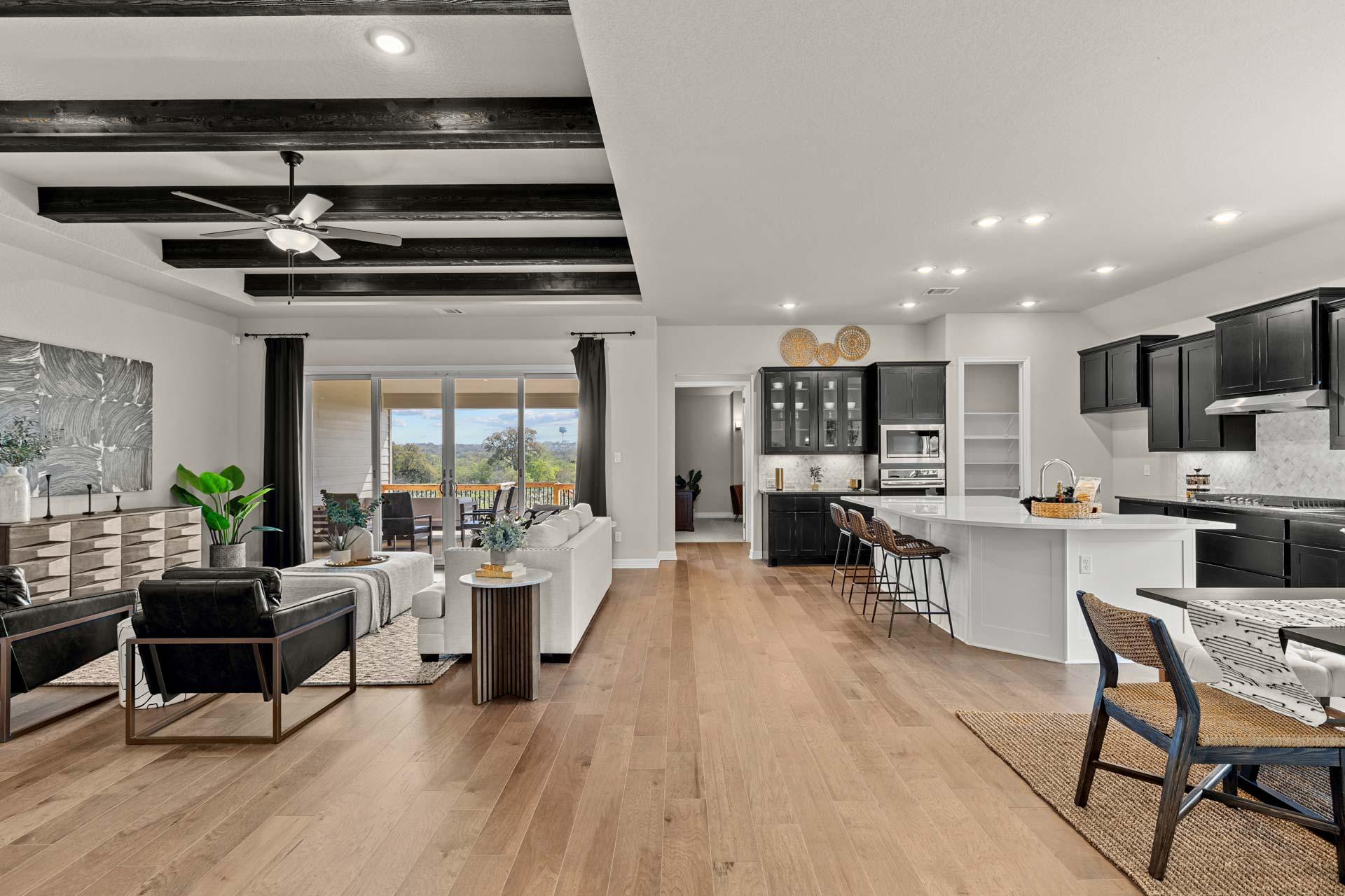 Open-concept living room and kitchen at Potranco Oaks in Castroville, Texas with hardwood floors, beamed ceiling, and modern island