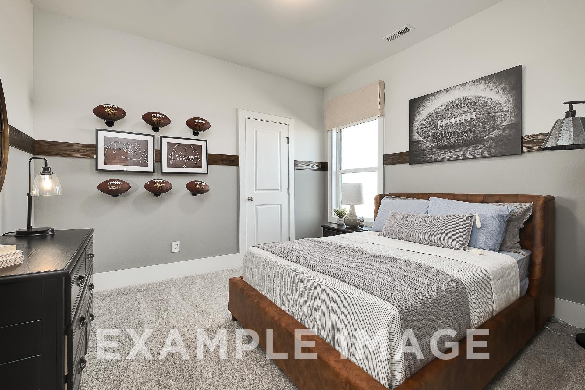 Football-themed bedroom in The Everett B showcasing queen bed with gray bedding, mounted footballs, and stadium artwork