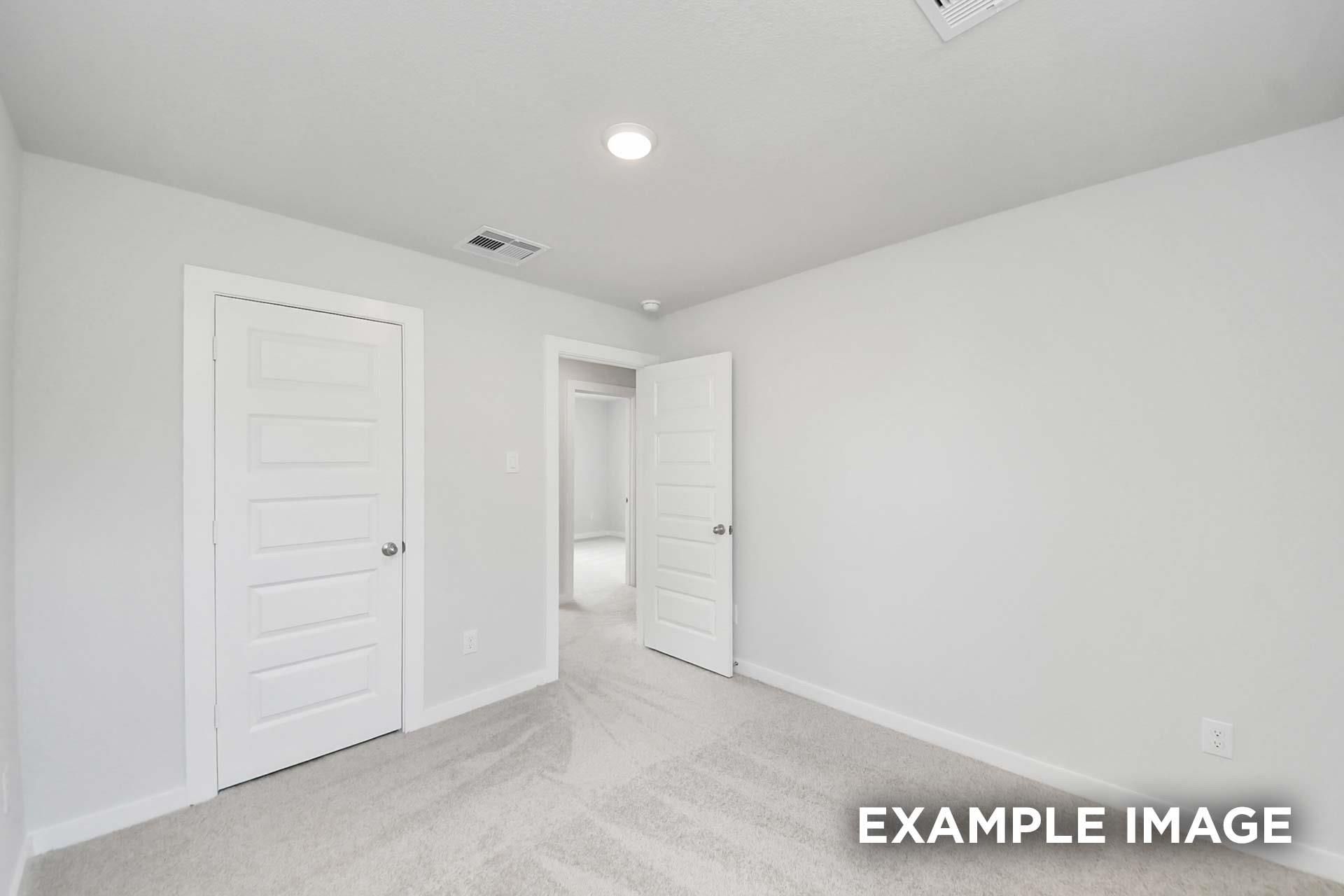 Bright carpeted bedroom with white panel doors in The Blanco E floor plan by Davidson Homes, Windmill Estates, Magnolia, Texas