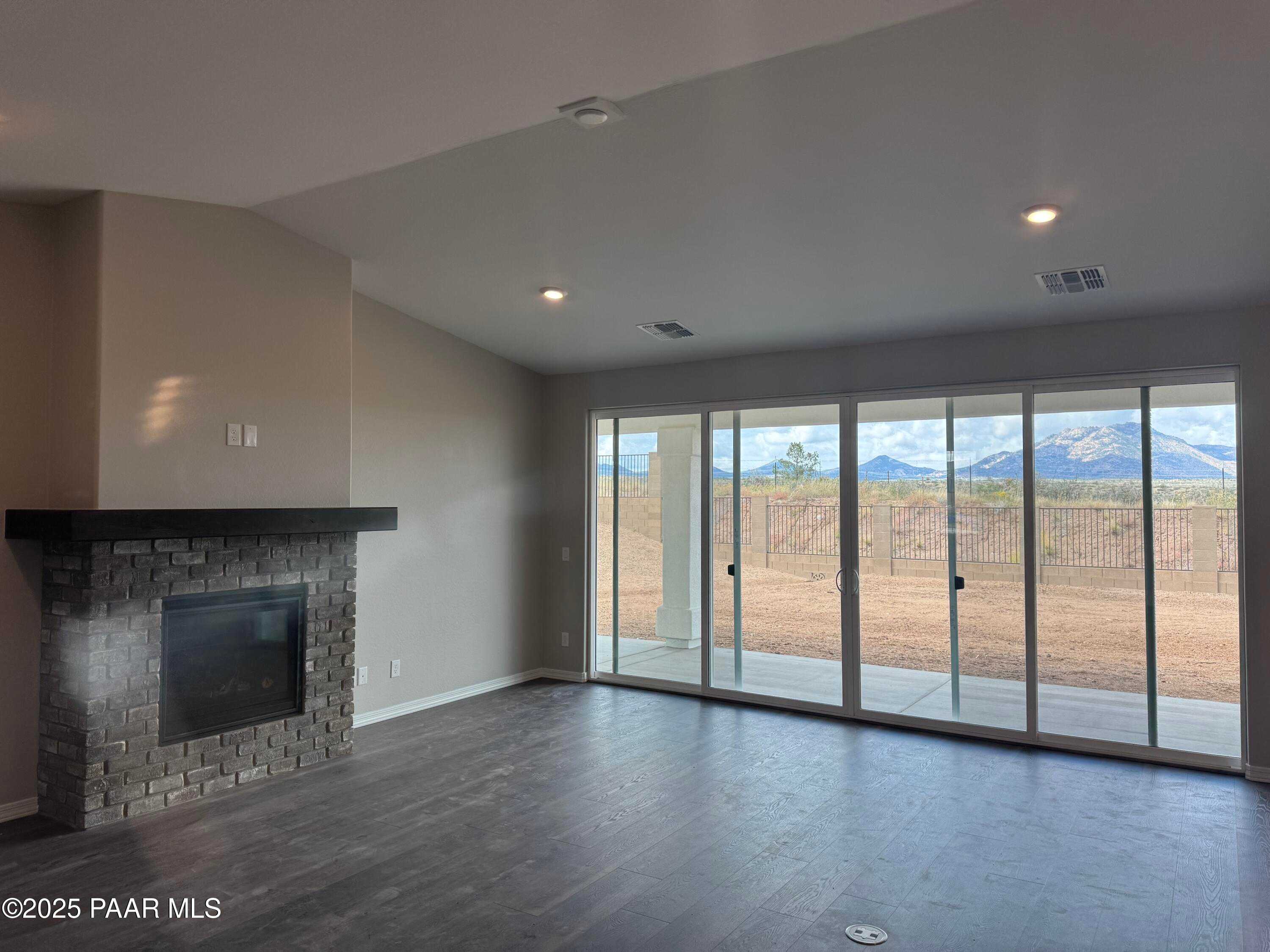 Spacious great room with stone fireplace and desert mountain views through sliding doors in Davidson Homes The Monarch E, Prescott, AZ