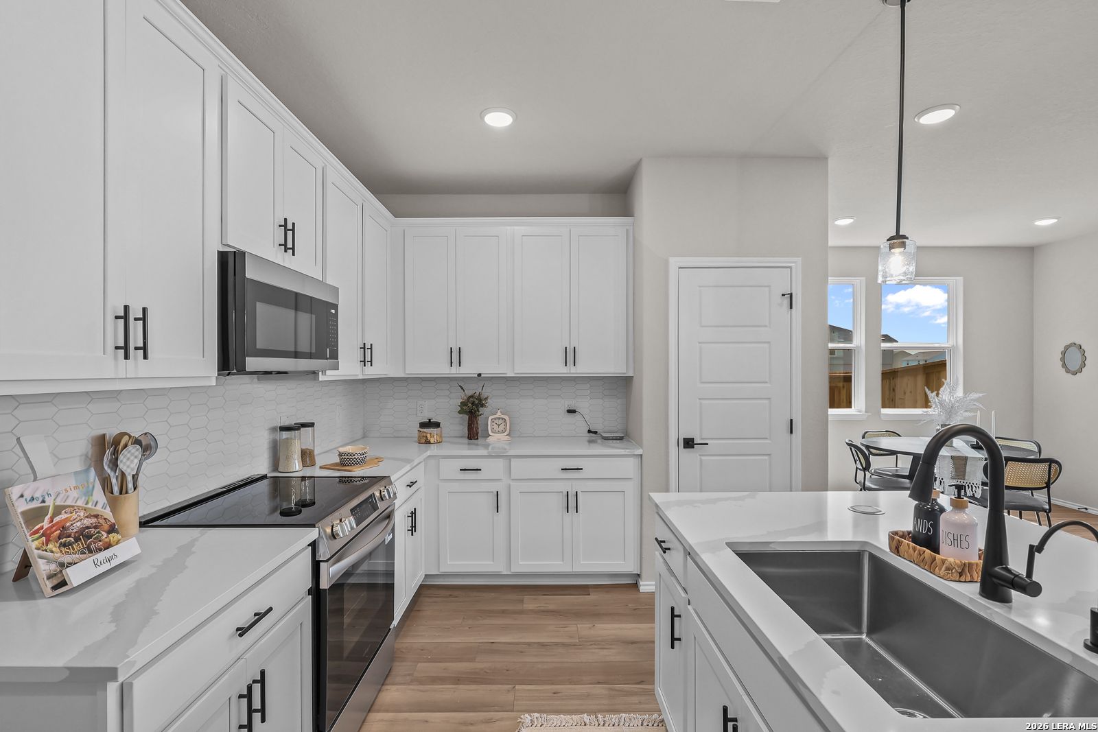 Modern kitchen with white cabinets, quartz countertops, and stainless appliances in The Daphne H floor plan, Seguin, TX.