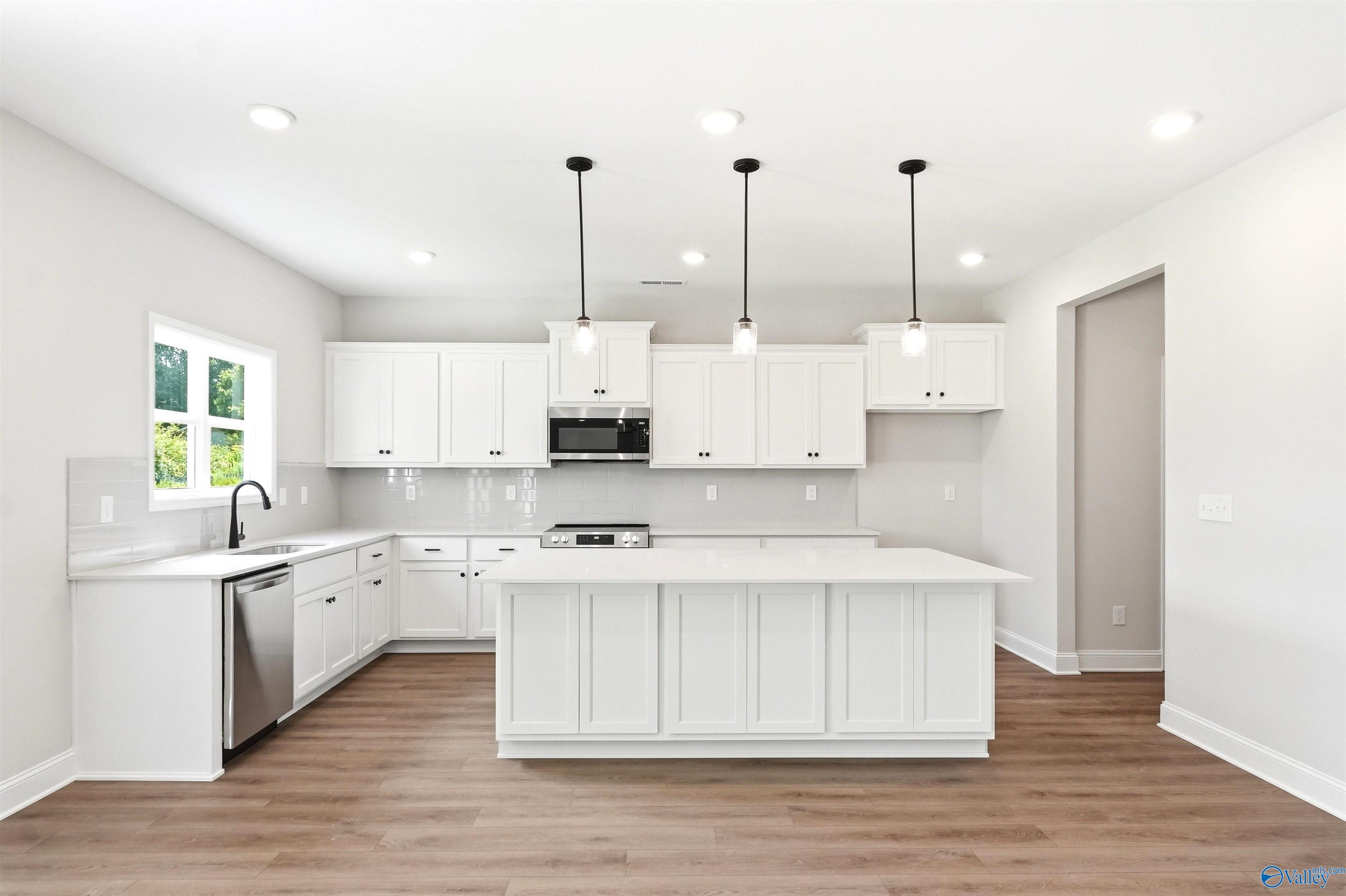 Modern kitchen with white cabinets, island, and pendant lighting in The Chelsea D floor plan at Berry Cove, New Market, AL.