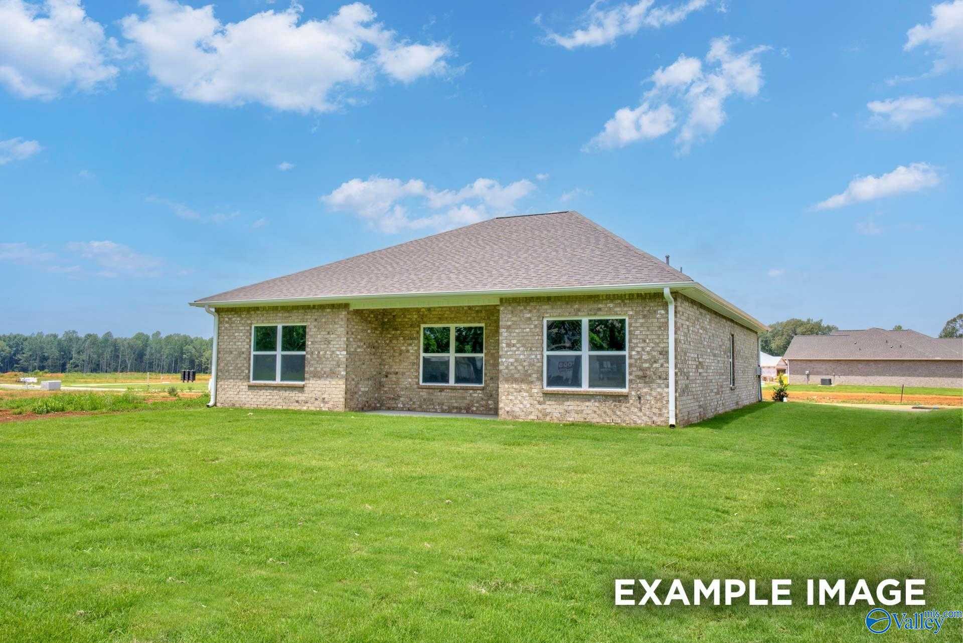 Tan brick 1-story ranch home exterior with covered porch, large windows, and lush green yard in Lynn Meadows, Meridianville, Alabama