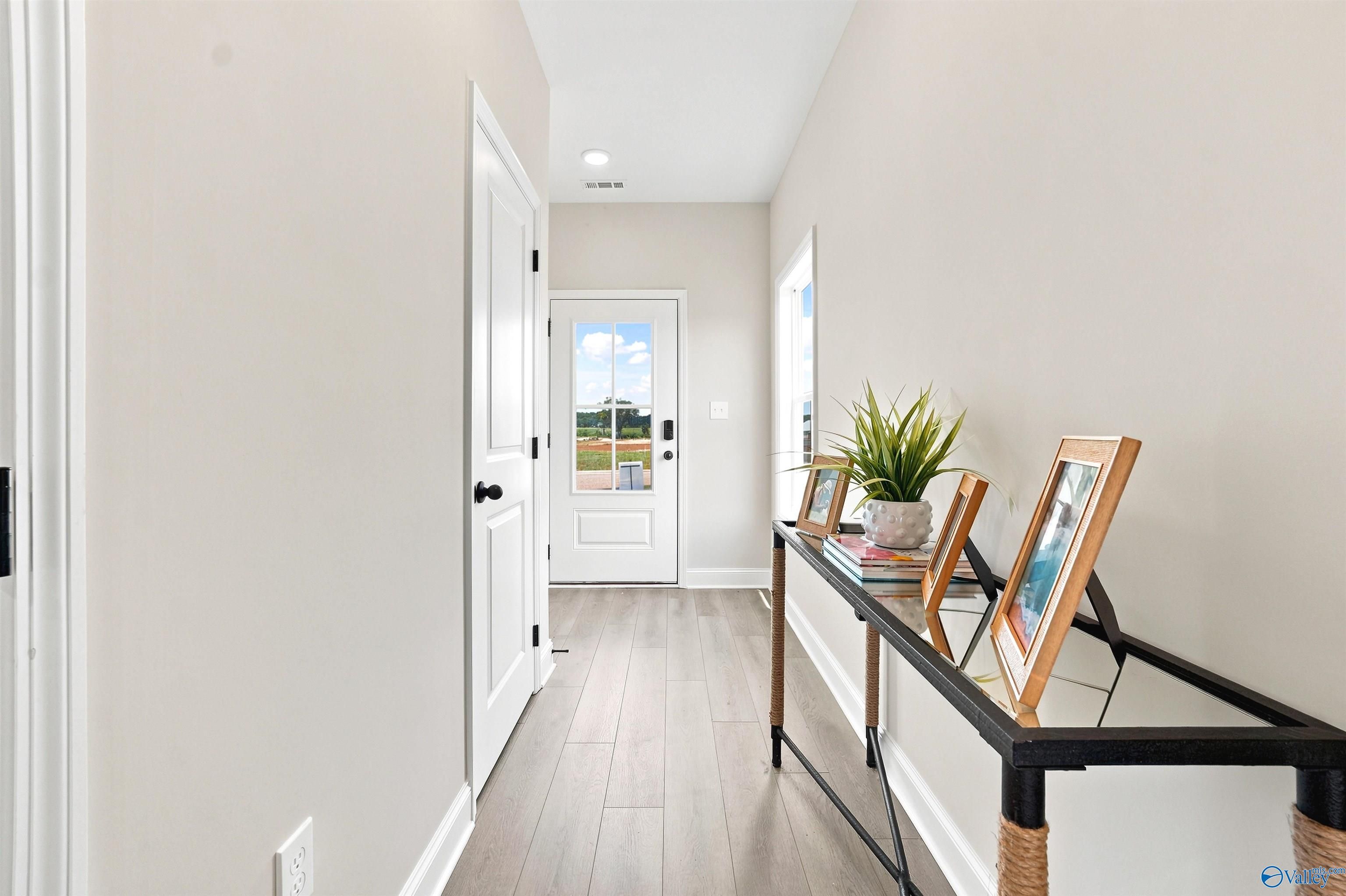 Bright entryway with wood-style flooring and modern console table in The Burton B floor plan at Heritage Lakes, Alabama.