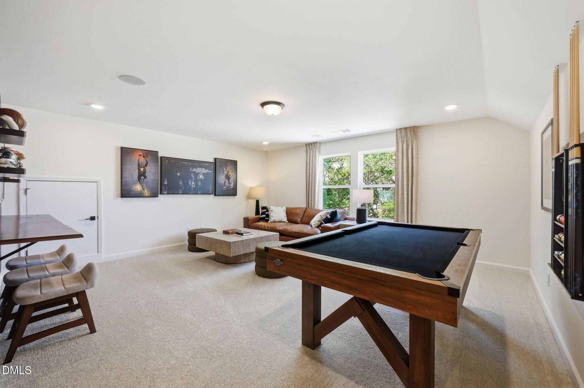Spacious game room with pool table and leather couch in The Aspen B floor plan at Wendell Ridge, Wendell, North Carolina.
