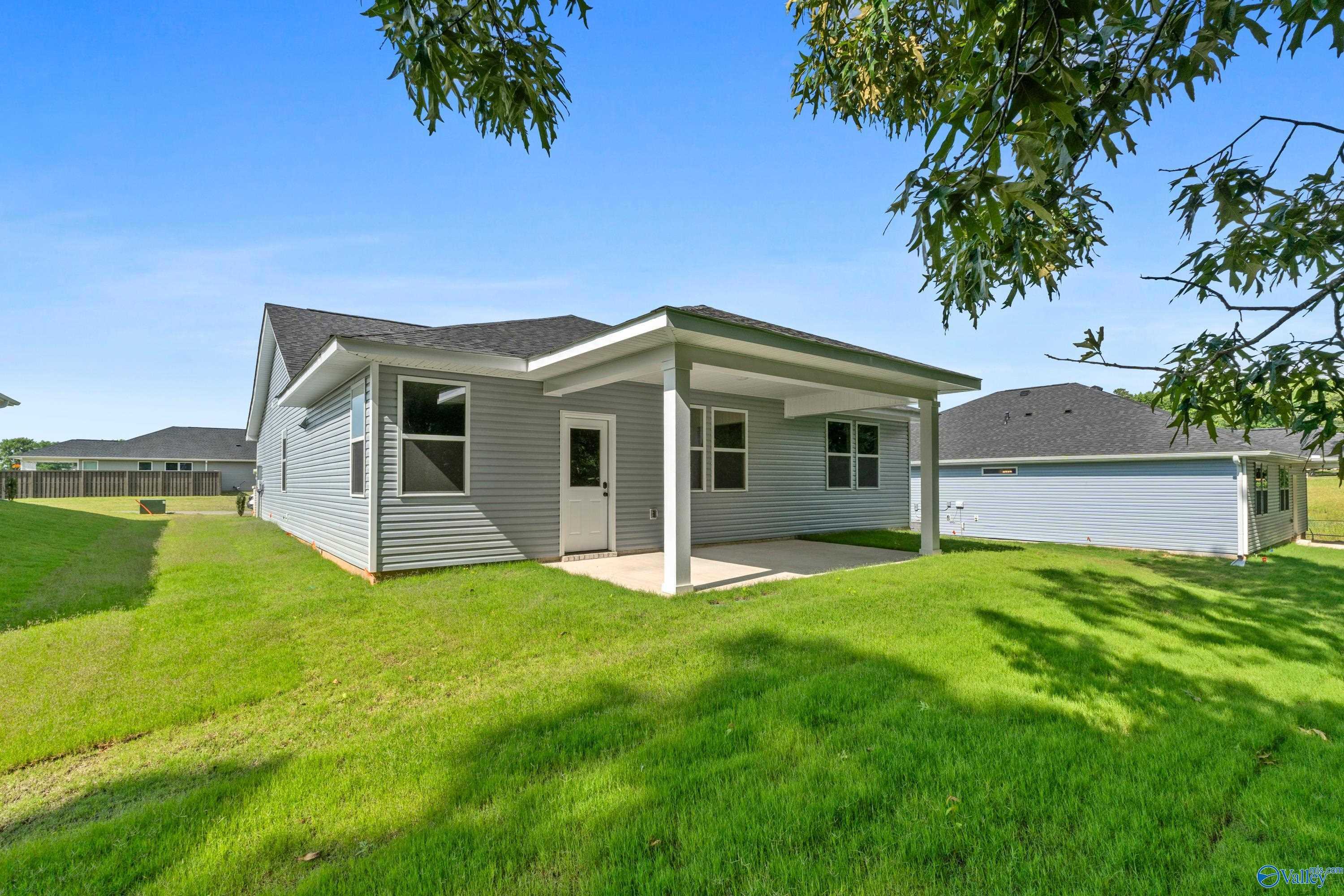 Gray single-story home exterior with covered patio, large windows, and lush green lawn in Bailey Park, Fayetteville, Tennessee